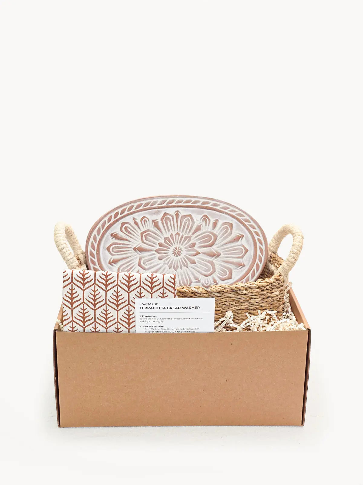 Terracotta bread warmer with floral design in woven basket, cozy farmhouse kitchen gift set