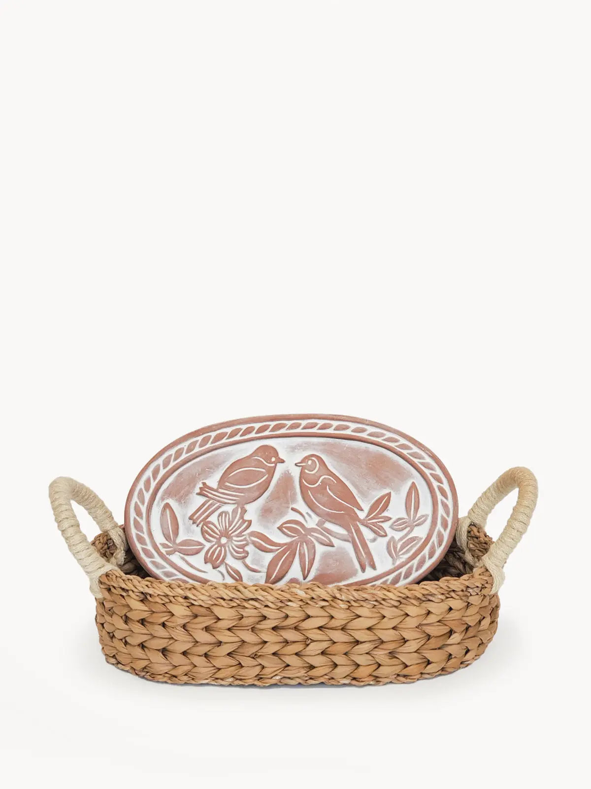 Woven seagrass basket with handles holding a ceramic plate featuring two birds and floral design, perfect for farmhouse decor.