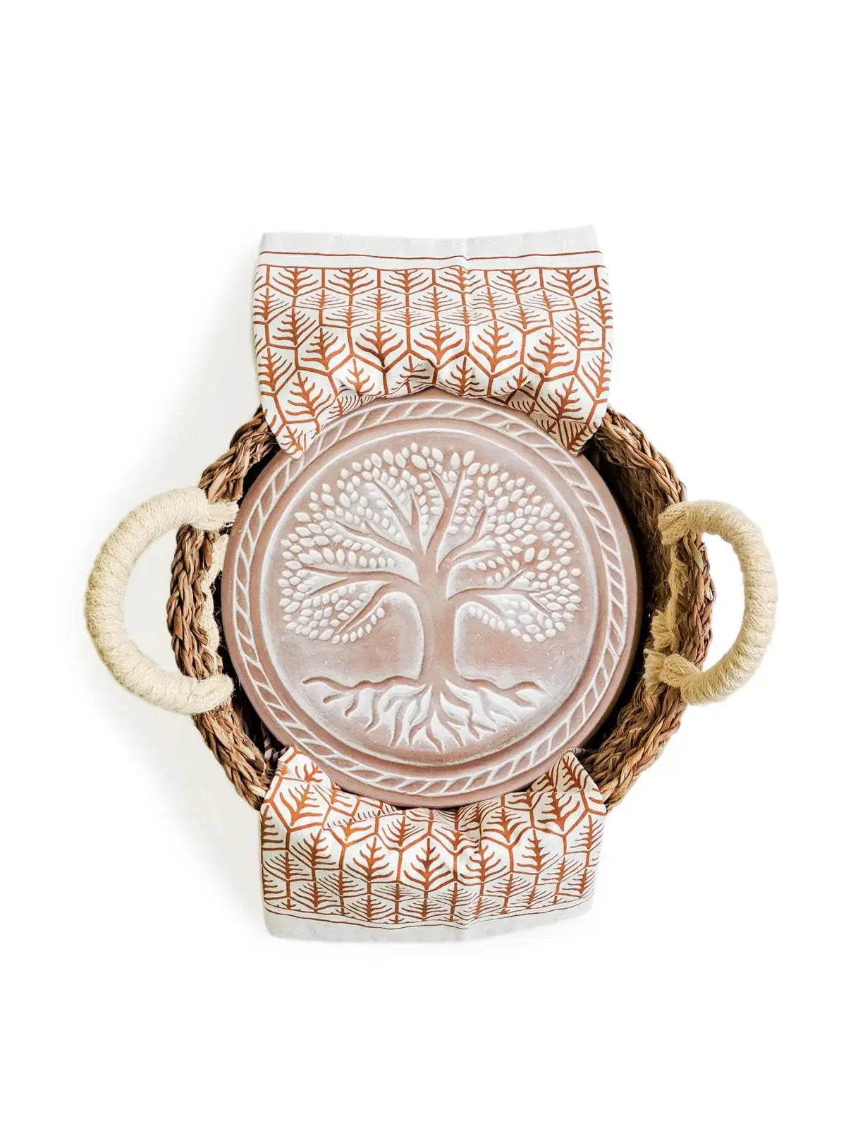 Woven basket with tree of life ceramic plate and leaf-patterned napkins, cozy farmhouse decor