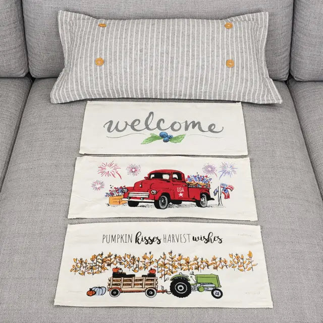 Decorative towels with truck designs and 'welcome' text on a gray couch.