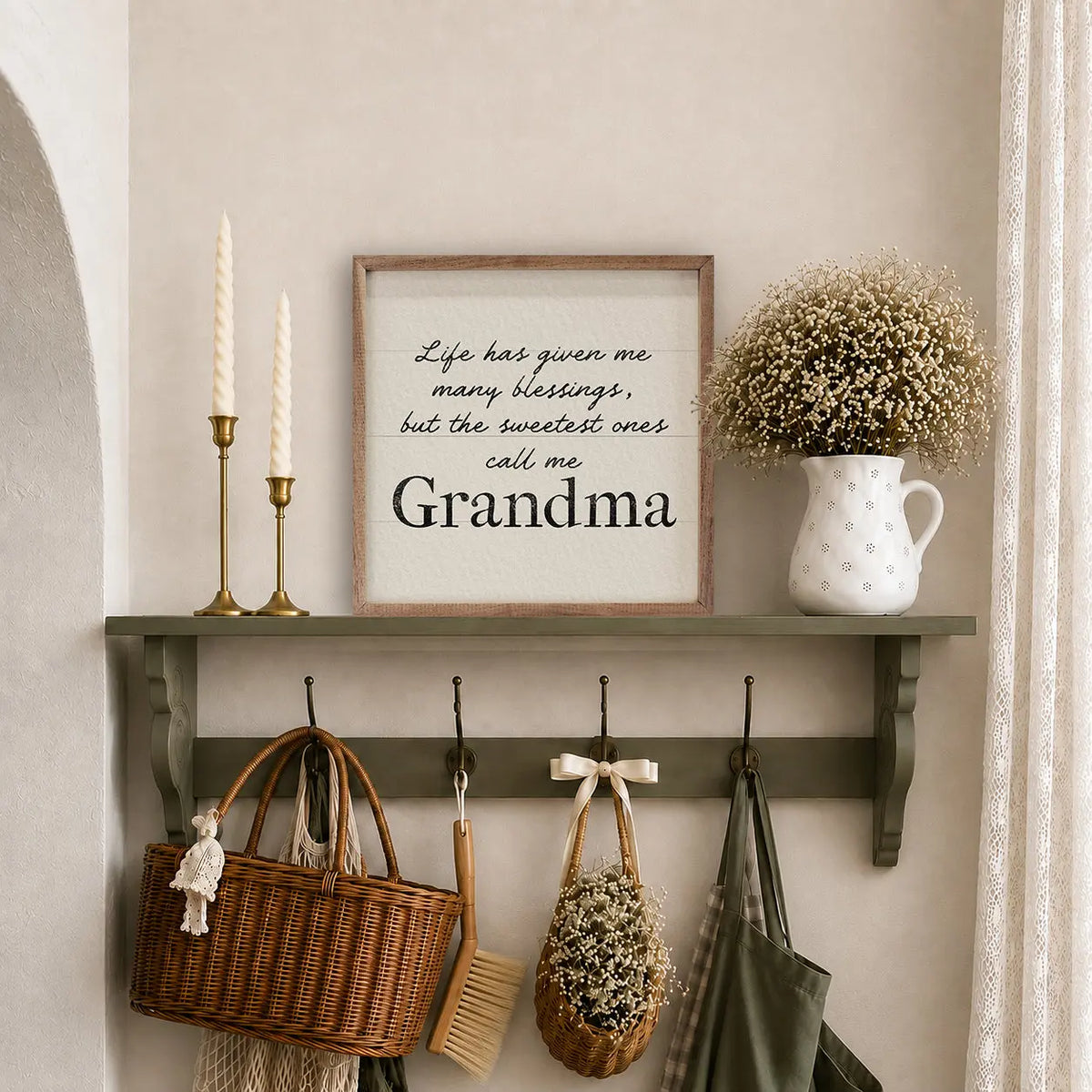 A framed wall sign with the text 'Life has given me many blessings, but the sweetest ones call me Grandpa' displayed on a dark green shelf in a cozy interior setting with candles, a white pitcher of baby's breath, and hanging baskets and bags below.