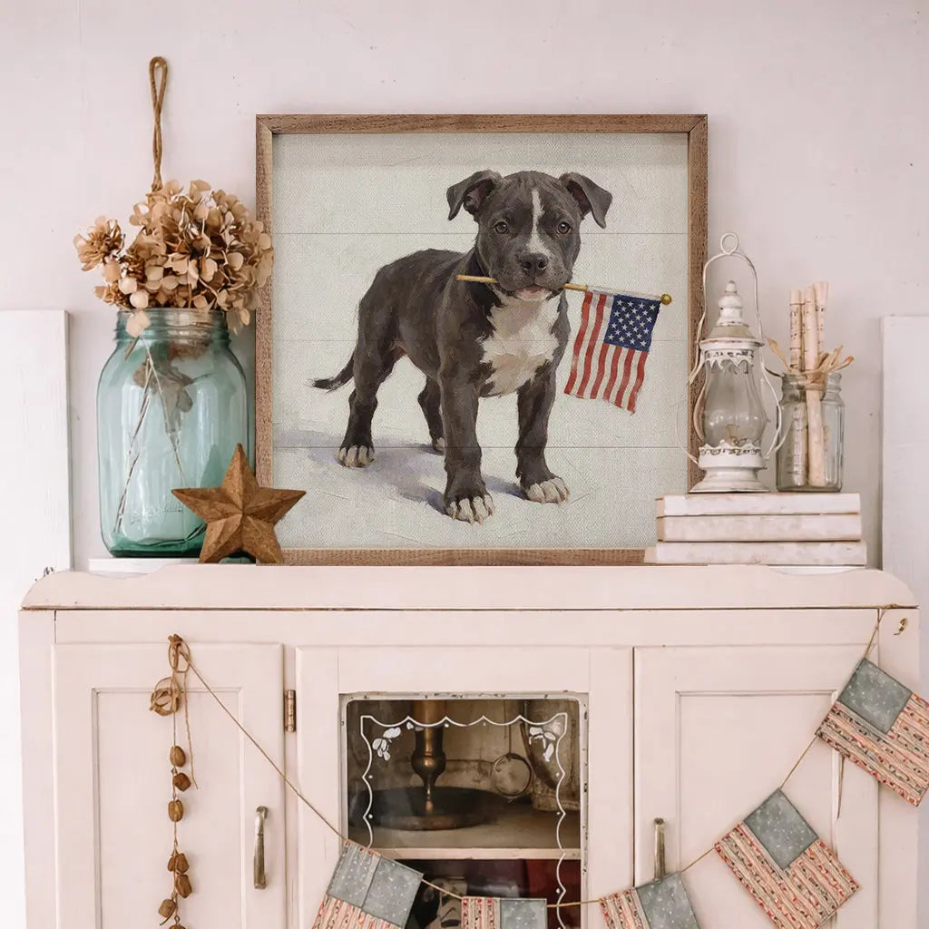 Framed picture of a dog with an American flag on a decorative shelf.