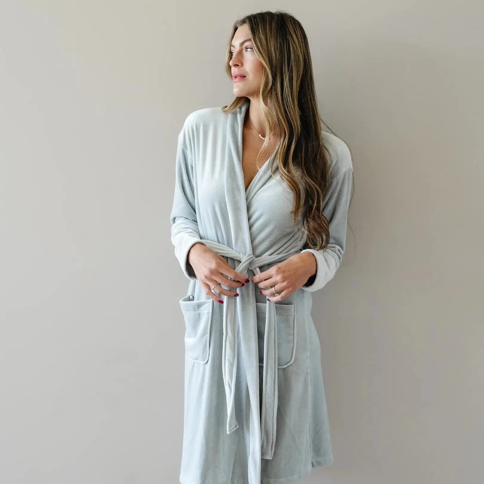 Woman in soft light blue plush robe with pockets, cozy bathrobe for relaxation and comfort