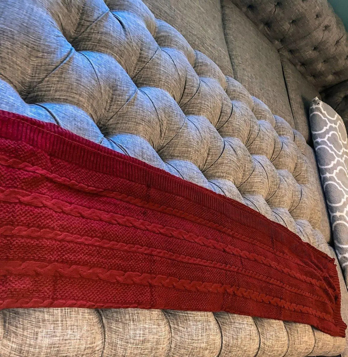 Cozy red knitted blanket draped on tufted farmhouse-style sofa for warm, inviting home decor