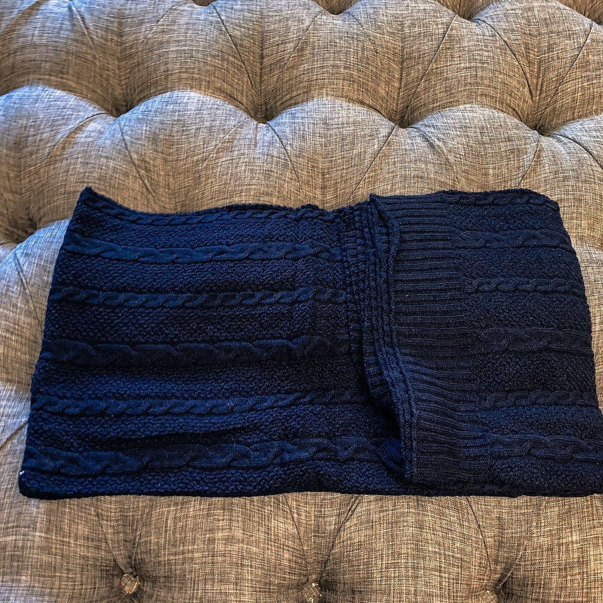 Cozy navy blue cable knit throw blanket on tufted sofa, farmhouse decor
