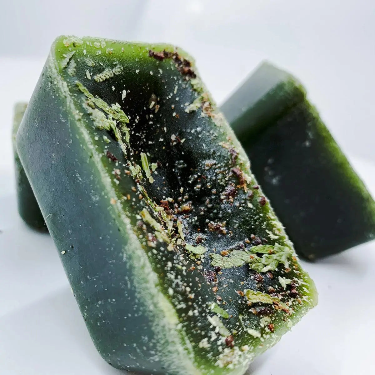 Green soap bar with specks on a white background