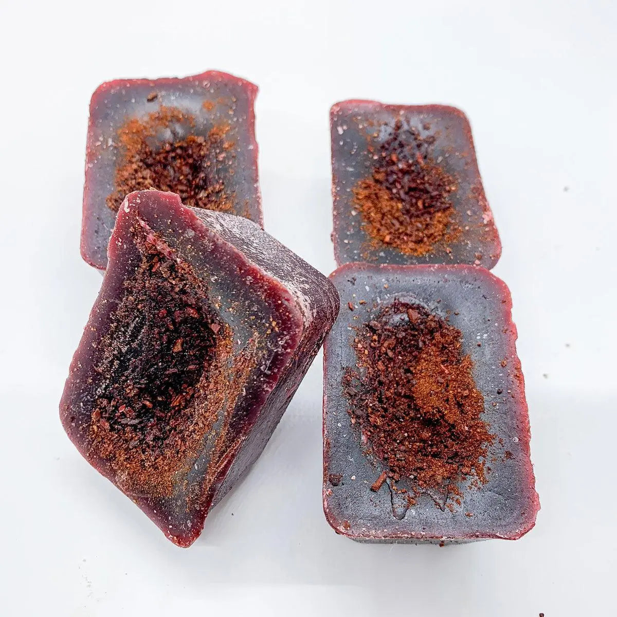 Four rectangular pieces of dark chocolate with a crumbly texture on a white background