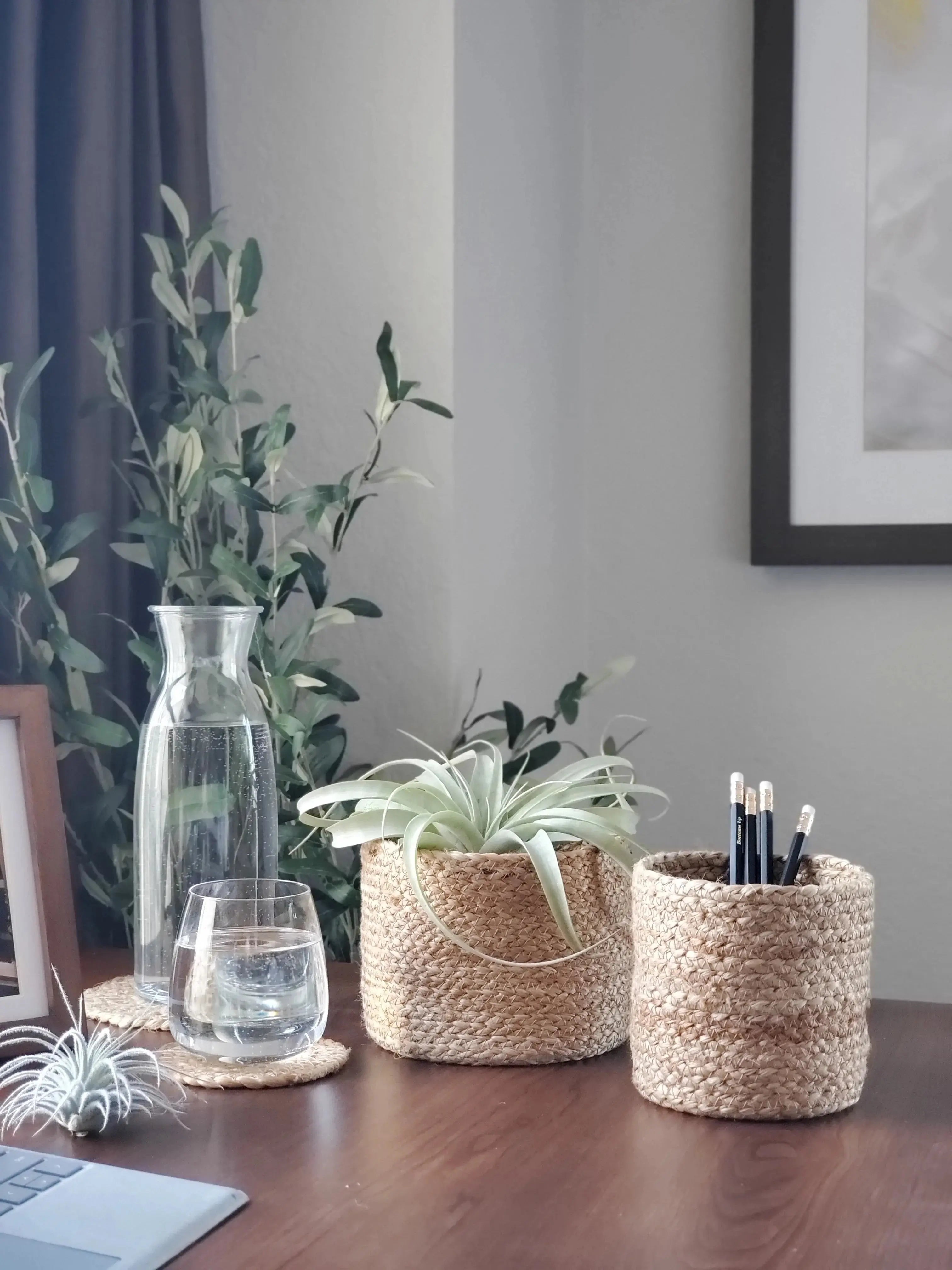 Woven baskets with air plants and pencils, cozy farmhouse desk decor with glass carafe and greenery