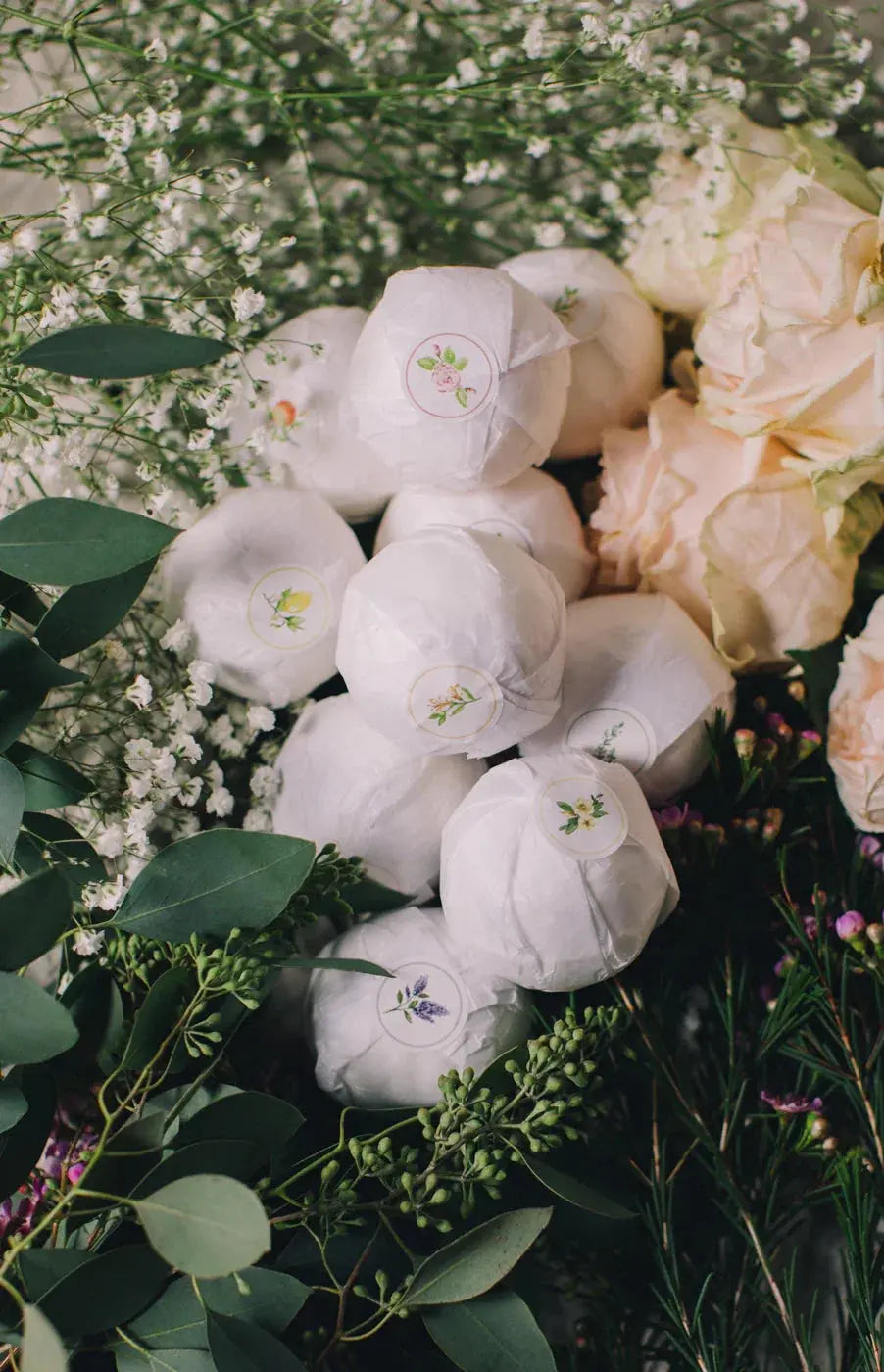 Cozy farmhouse bath bombs with floral labels nestled in baby's breath and eucalyptus greenery