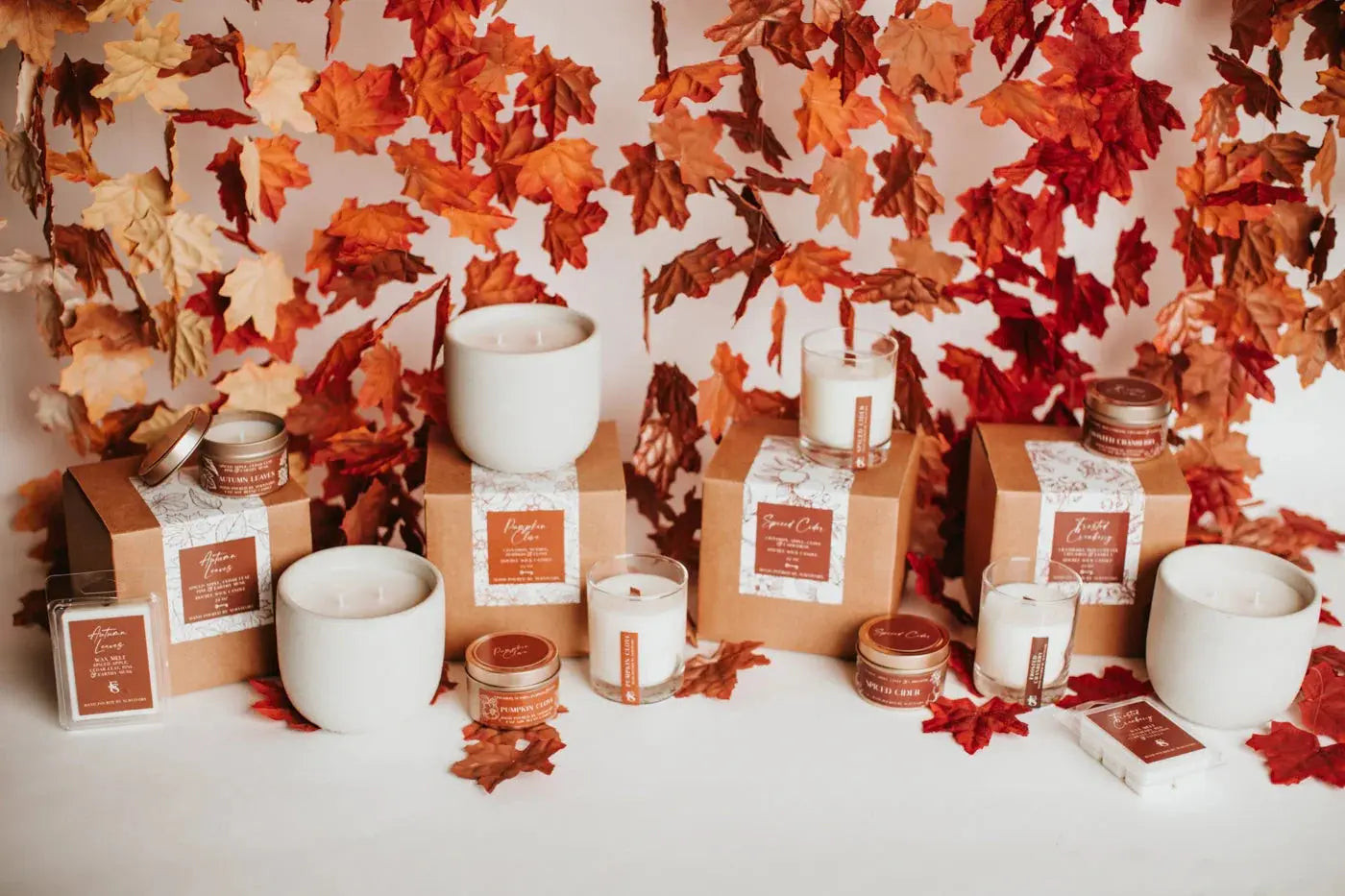Fall-themed candles and wax melts in cozy farmhouse style with autumn leaves backdrop