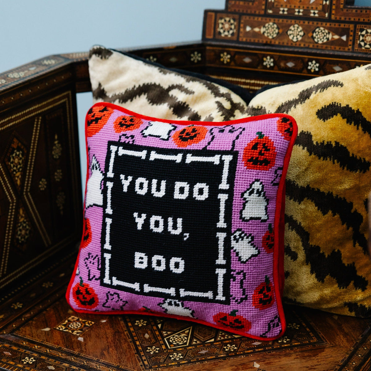 Decorative pillow with Halloween-themed design and text on a wooden surface.