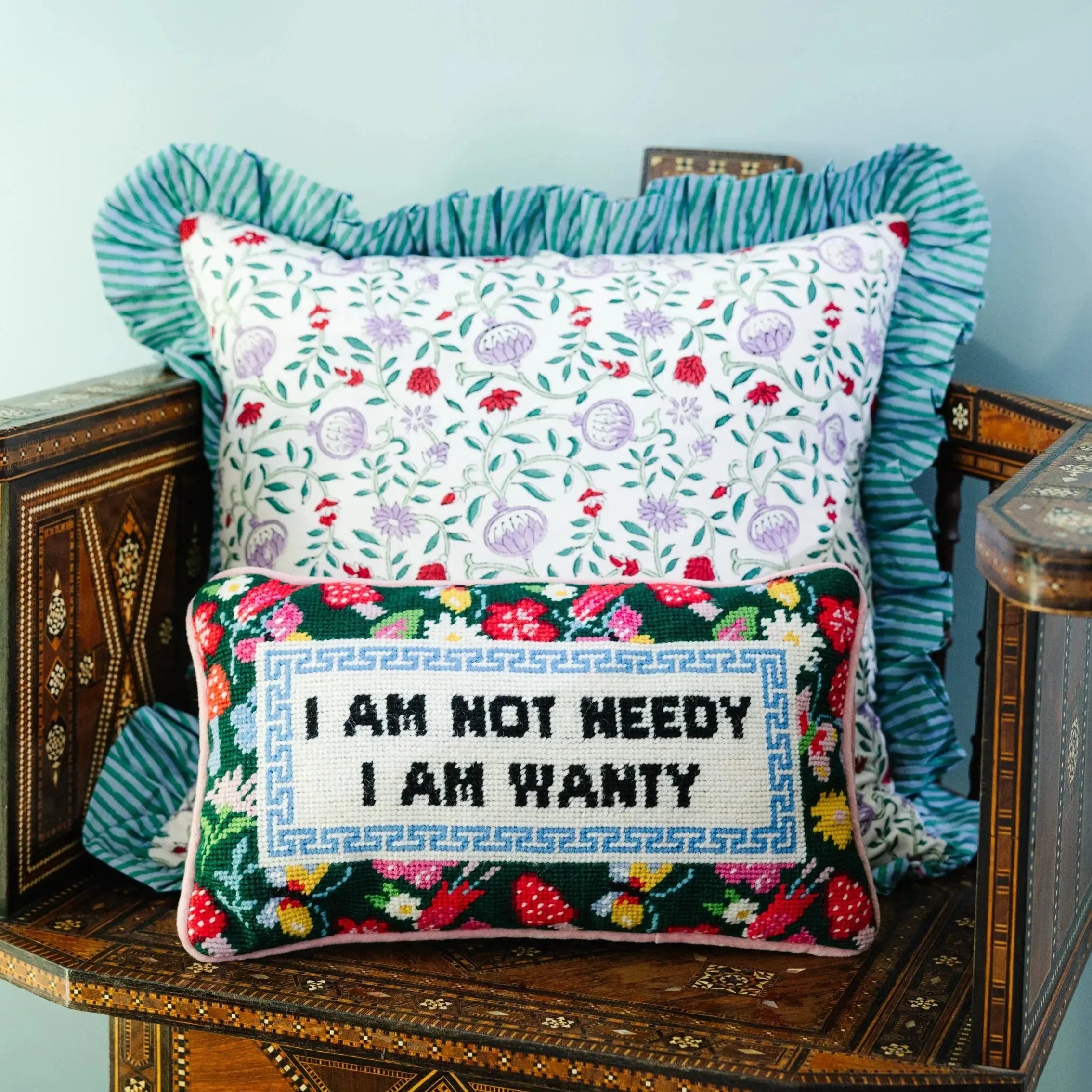Decorative pillows with floral patterns and text on a wooden surface.