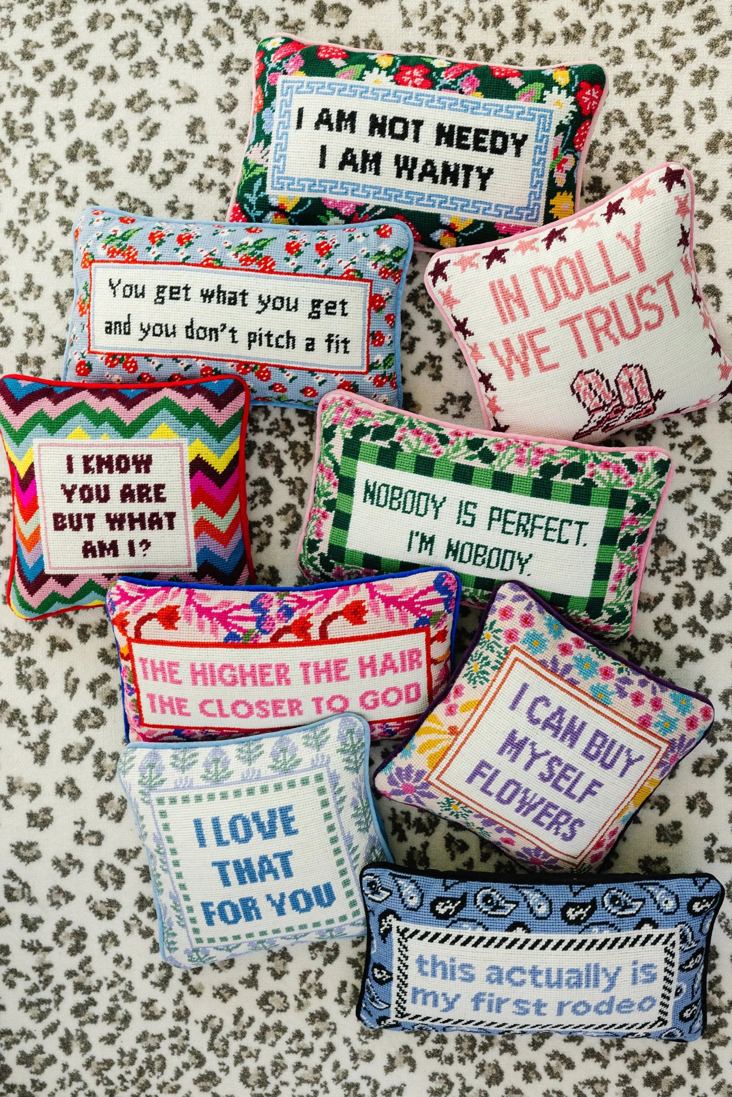 Decorative pillows with floral patterns and text on a leopard surface.