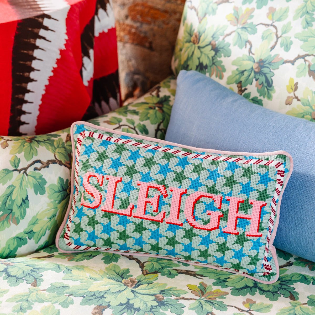 Decorative pillow with 'SLEIGH' text on a patterned sofa