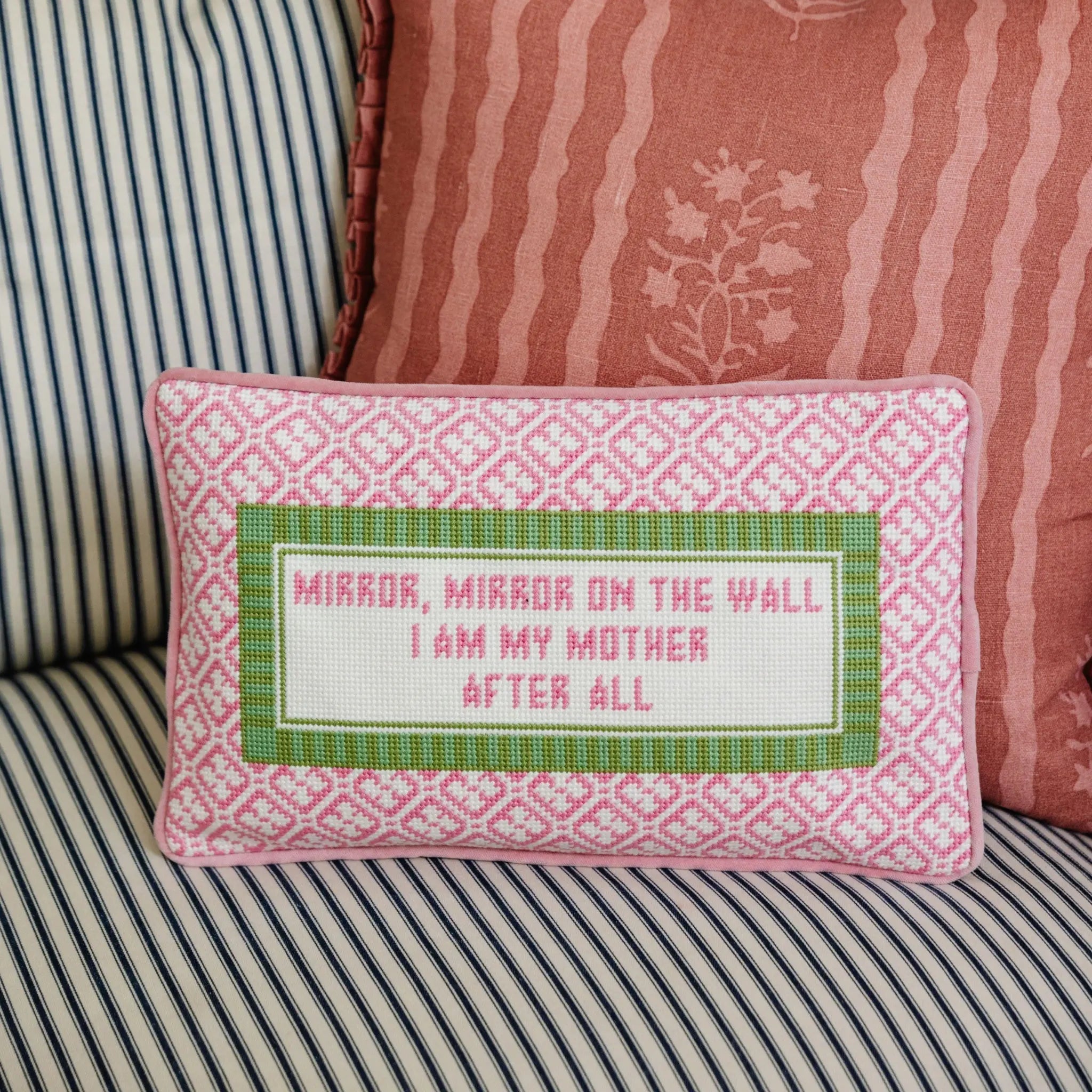 Decorative pillow with embroidered text on a striped sofa