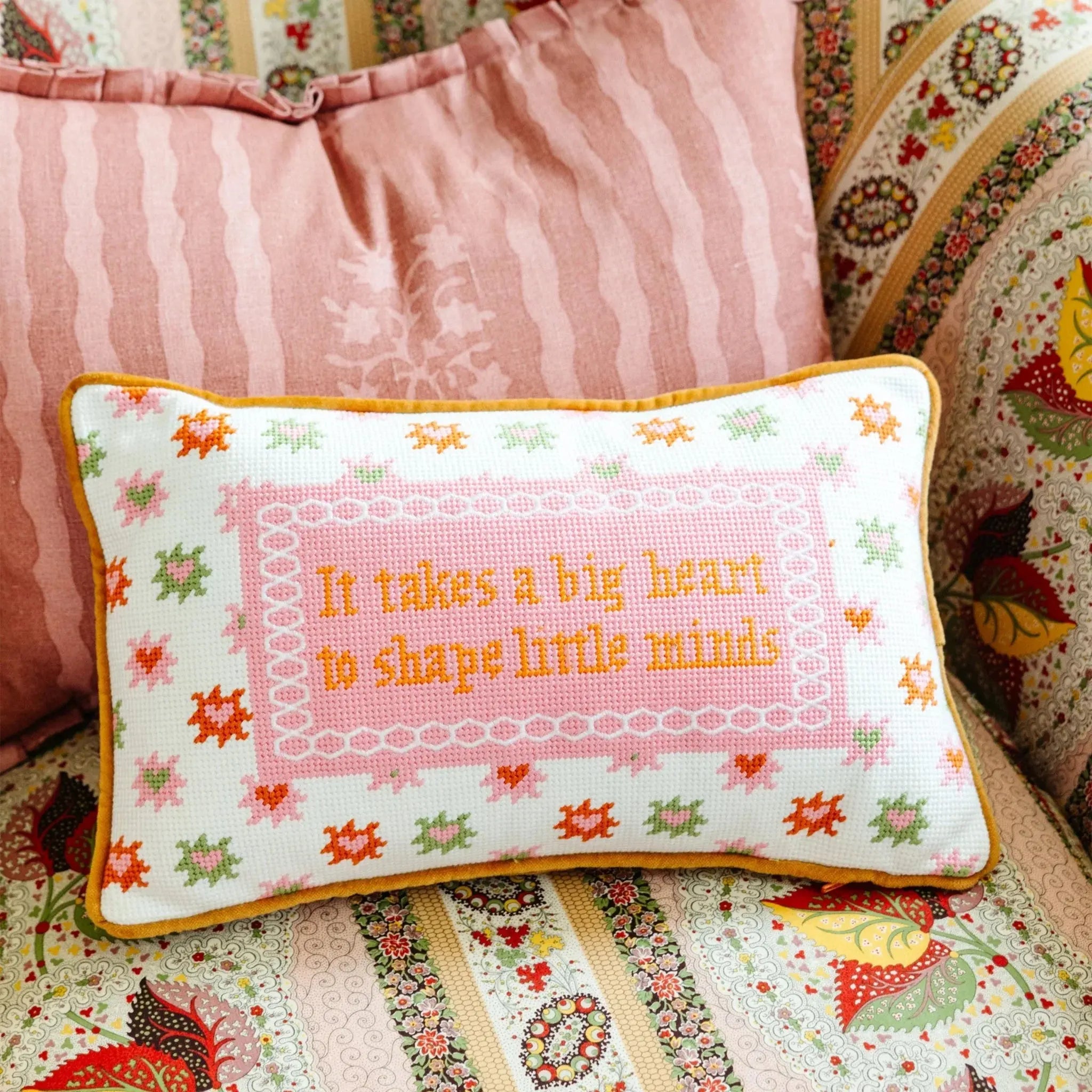 Decorative pillow with embroidered text on a patterned fabric background