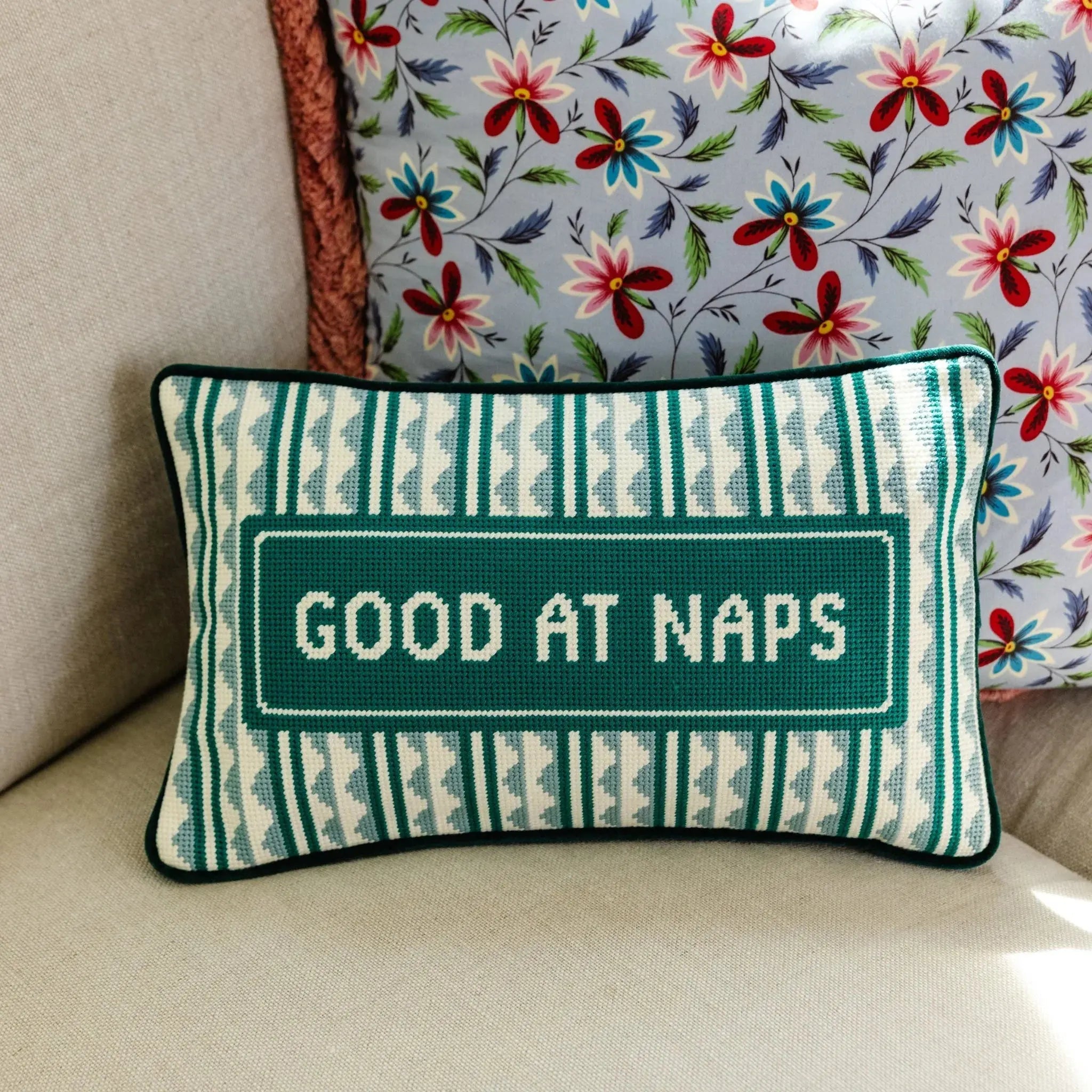 decorative pillow on a beige couch laying against a floral pillow