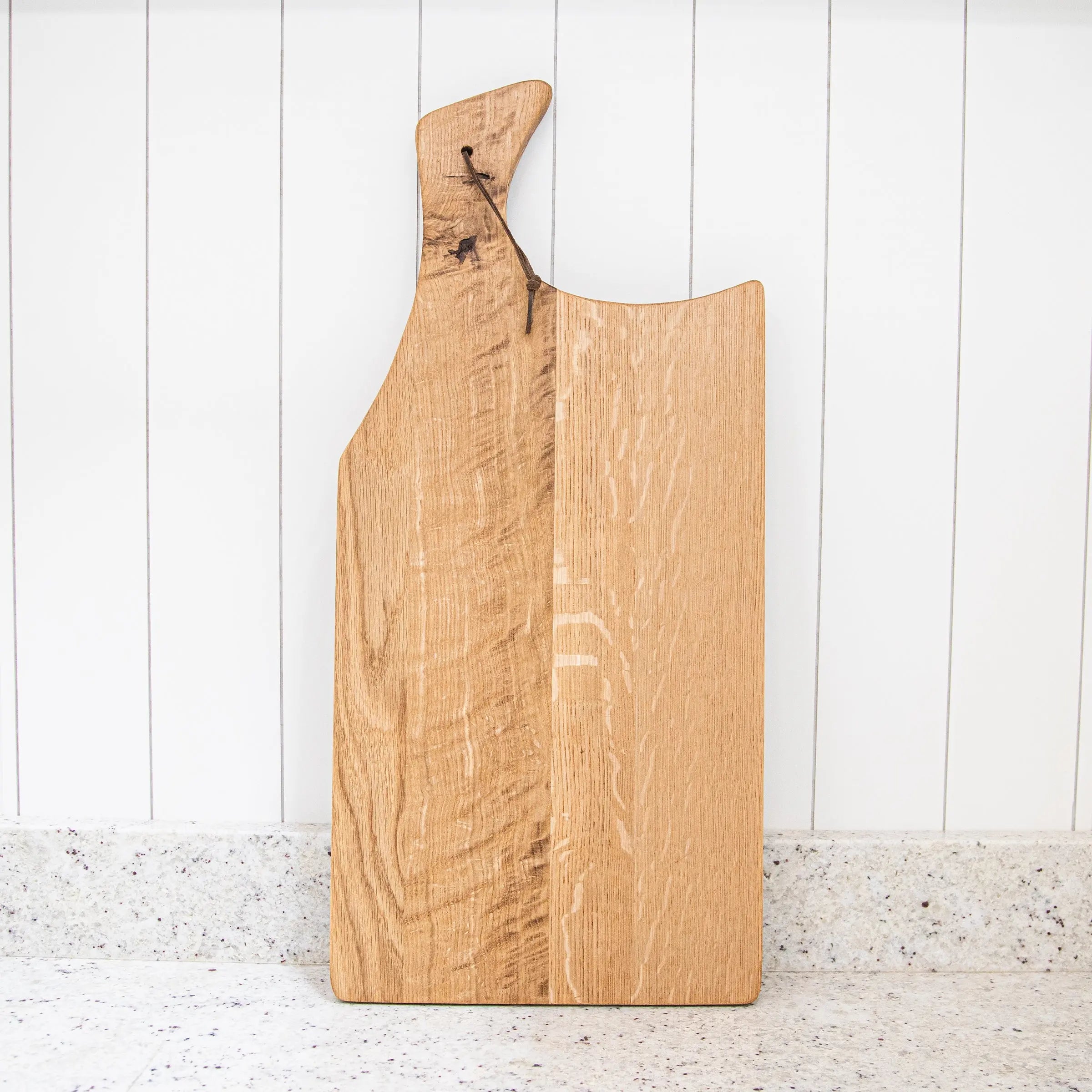 Wooden cutting board with a handle on a white surface