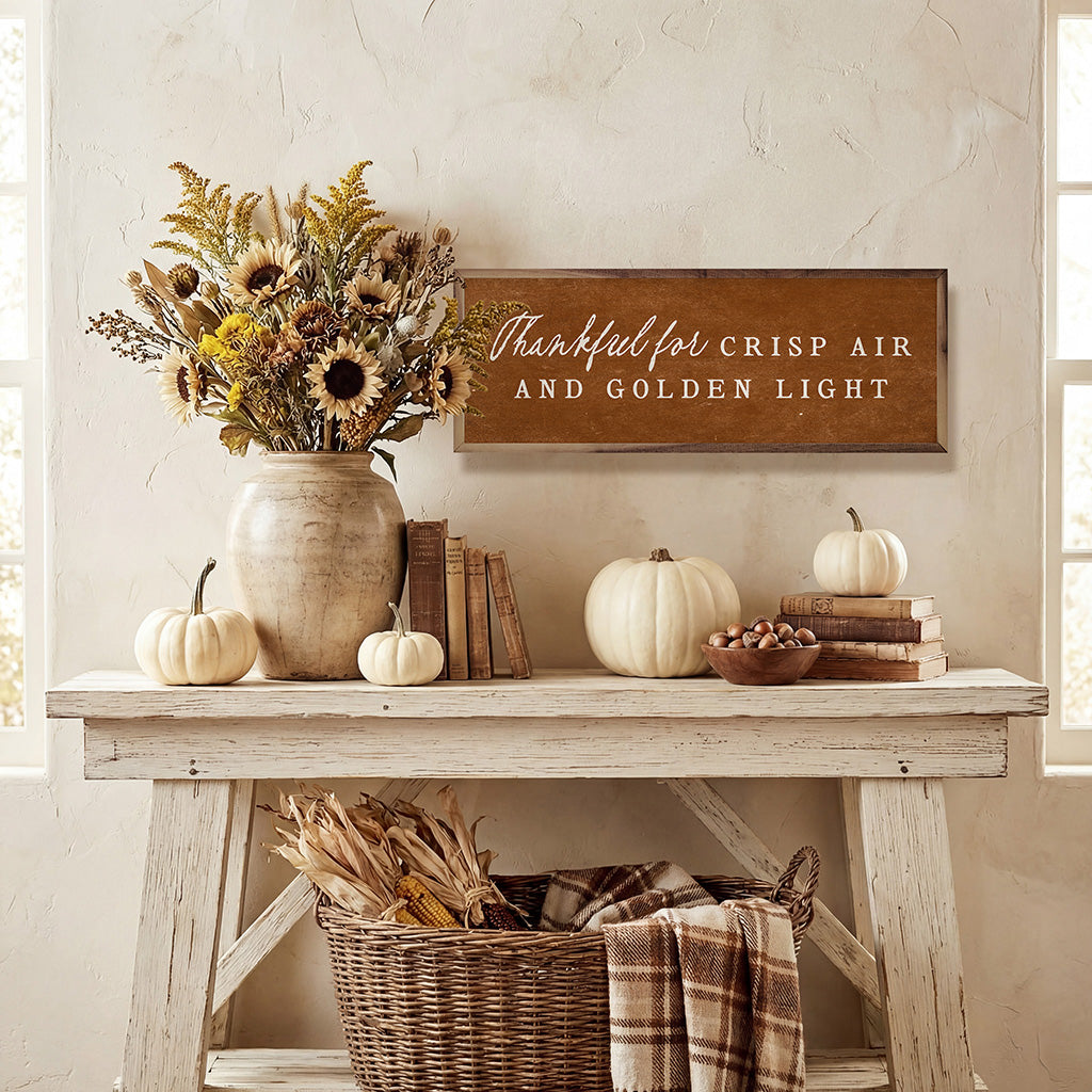 Autumn-themed decor with pumpkins, books, and a vase of flowers on a wooden table.