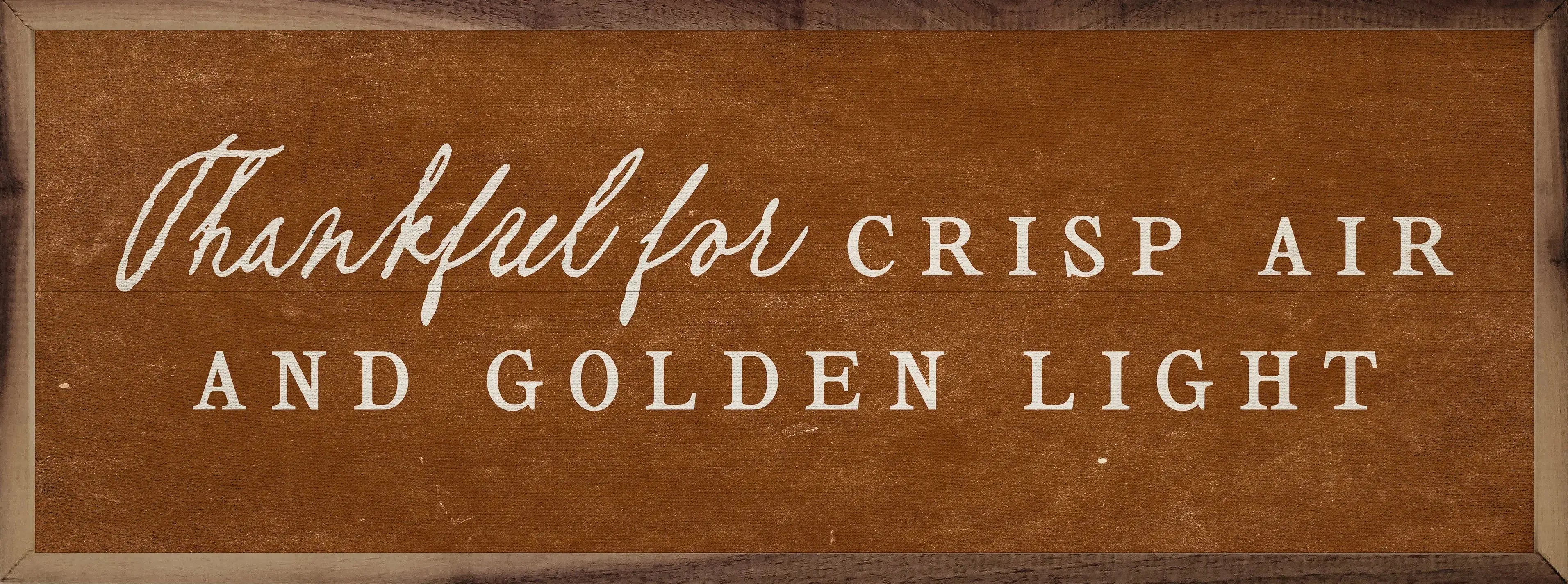 Wooden sign with text 'Thankful for Crisp Air and Golden Light' on a brown background
