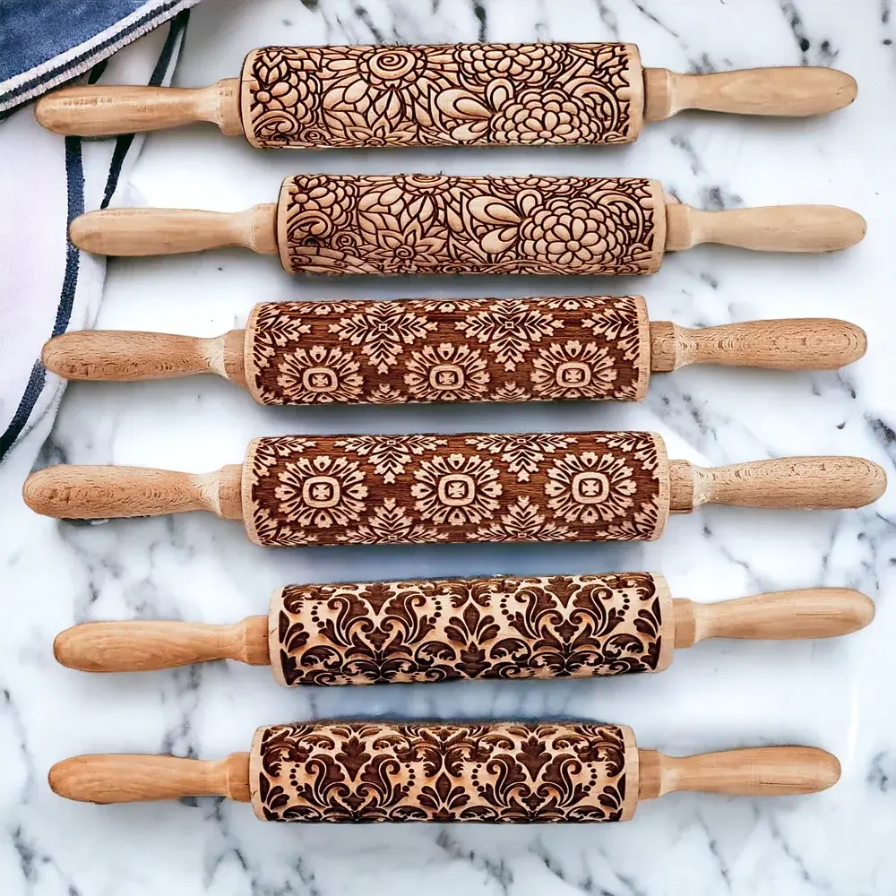 Set of six wooden rolling pins with embossed patterns on a marble surface