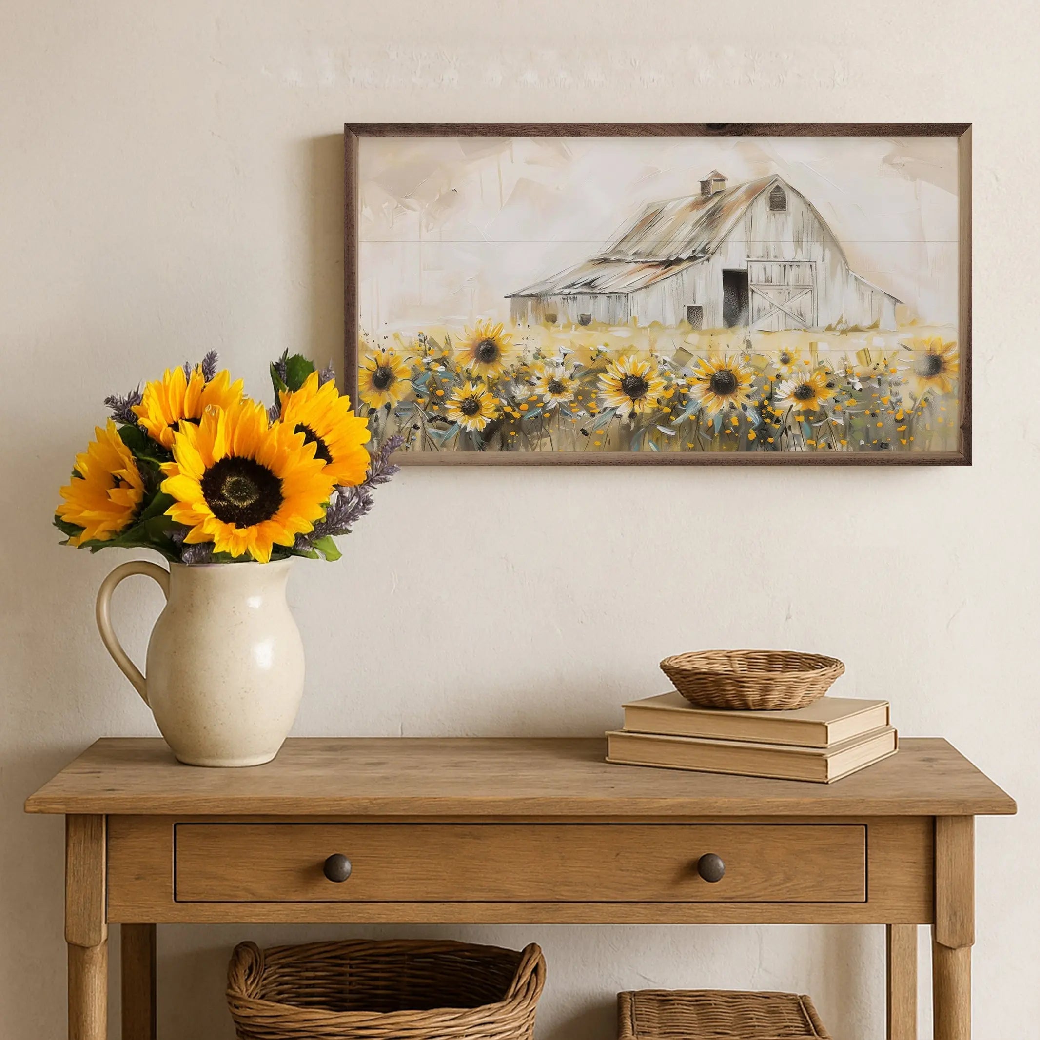Vase of sunflowers on a wooden table with a framed picture of a barn and field in the background.
