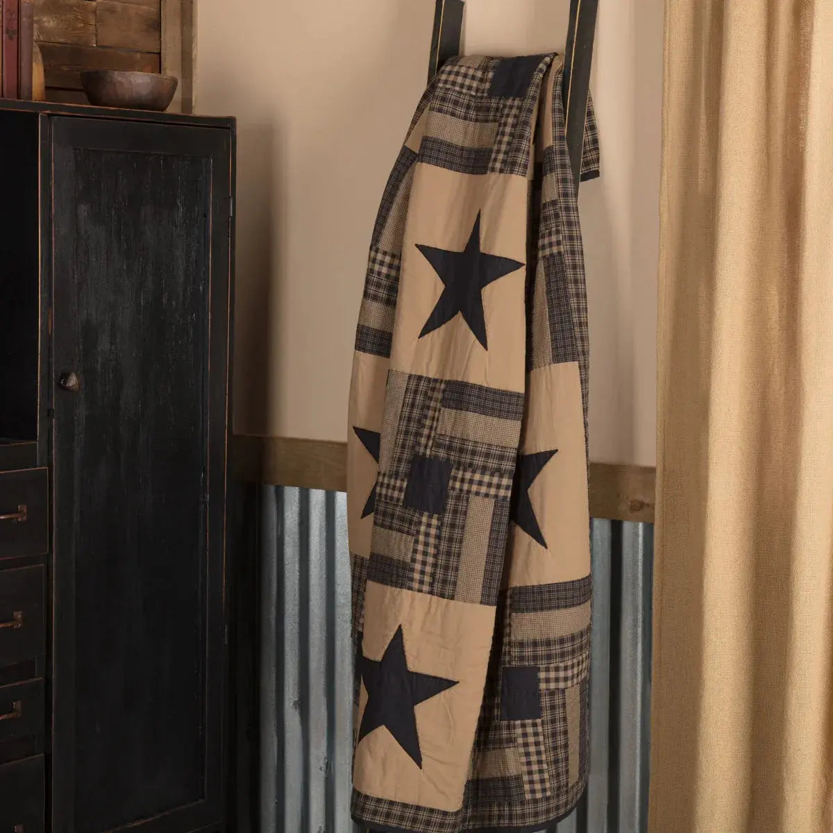 Plaid blanket with star patterns draped over a wooden surface next to a dark cabinet.