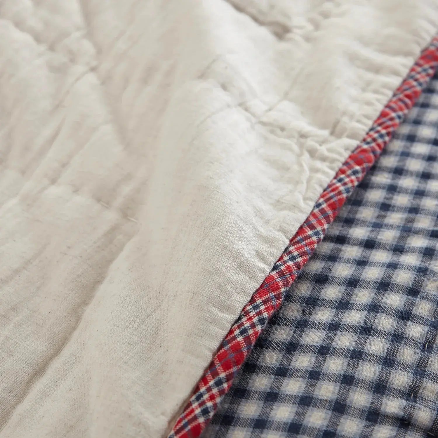 Cozy quilted throw blanket with red plaid trim and blue gingham pattern, perfect for farmhouse decor
