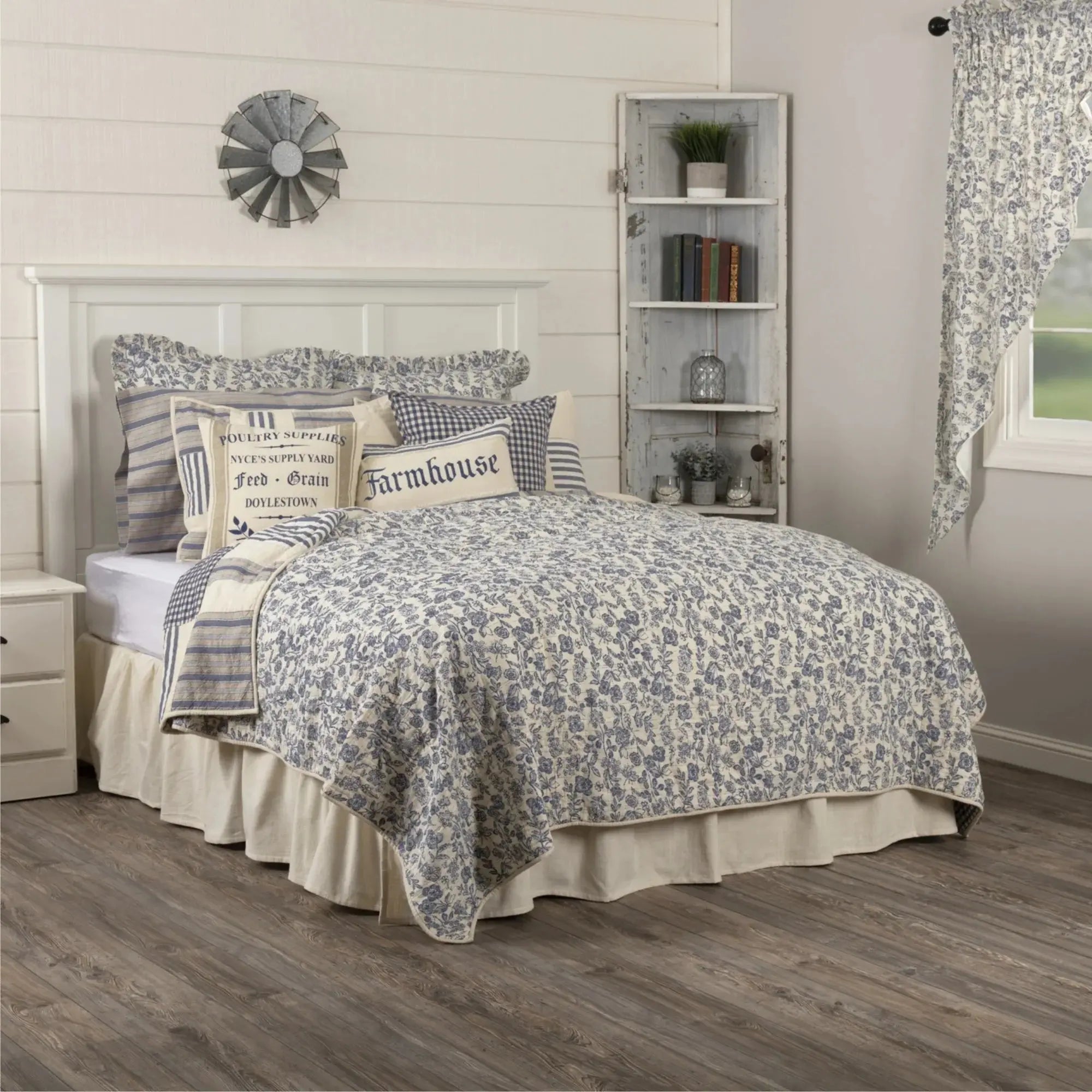 Cozy farmhouse bedroom with blue floral quilt, gingham pillows, and rustic decor for peaceful living spaces