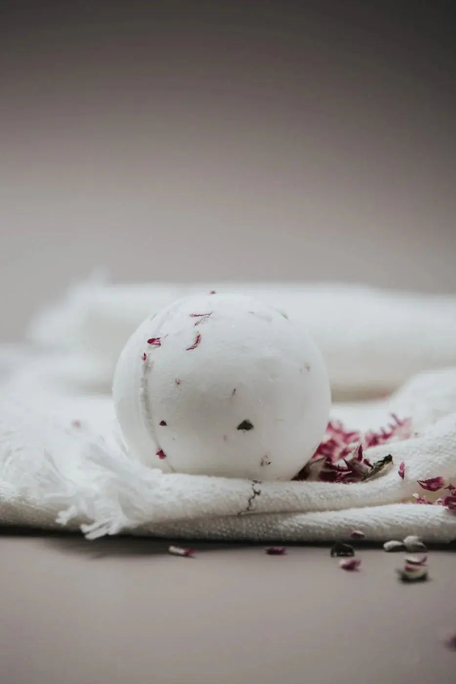 White bath bomb with dried rose petals on cozy towel, farmhouse spa essential