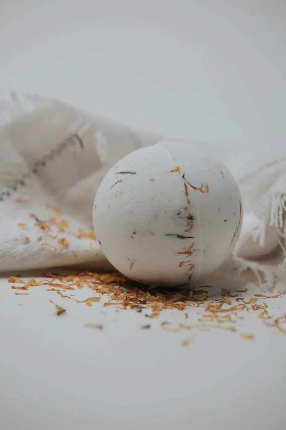 White bath bomb with dried flowers on cozy linen, farmhouse bath essentials