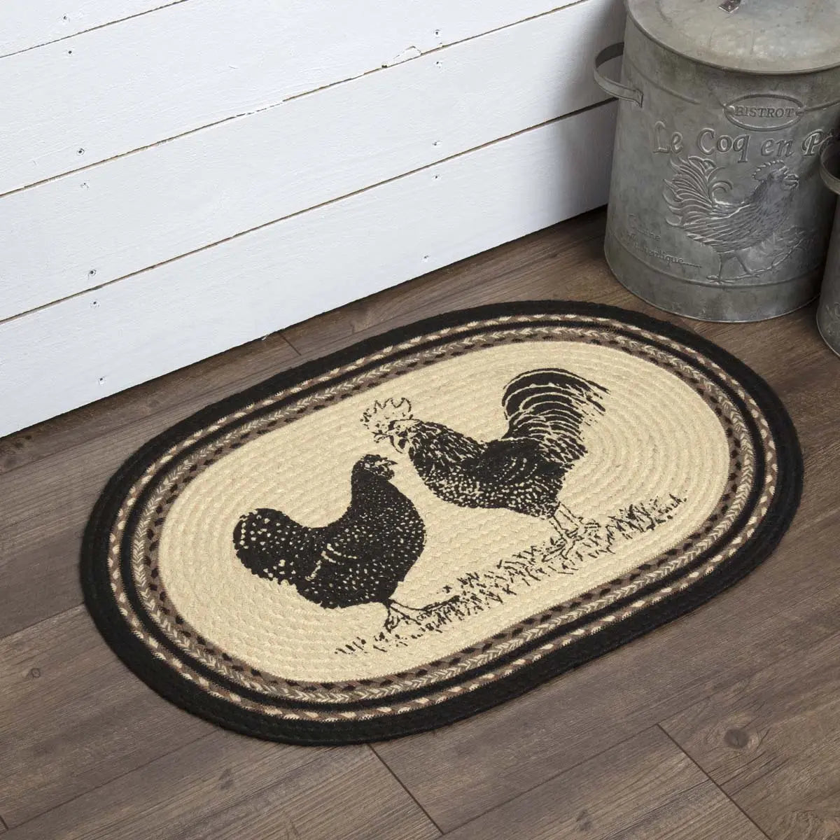 Oval-shaped doormat with rooster design on a wooden floor.