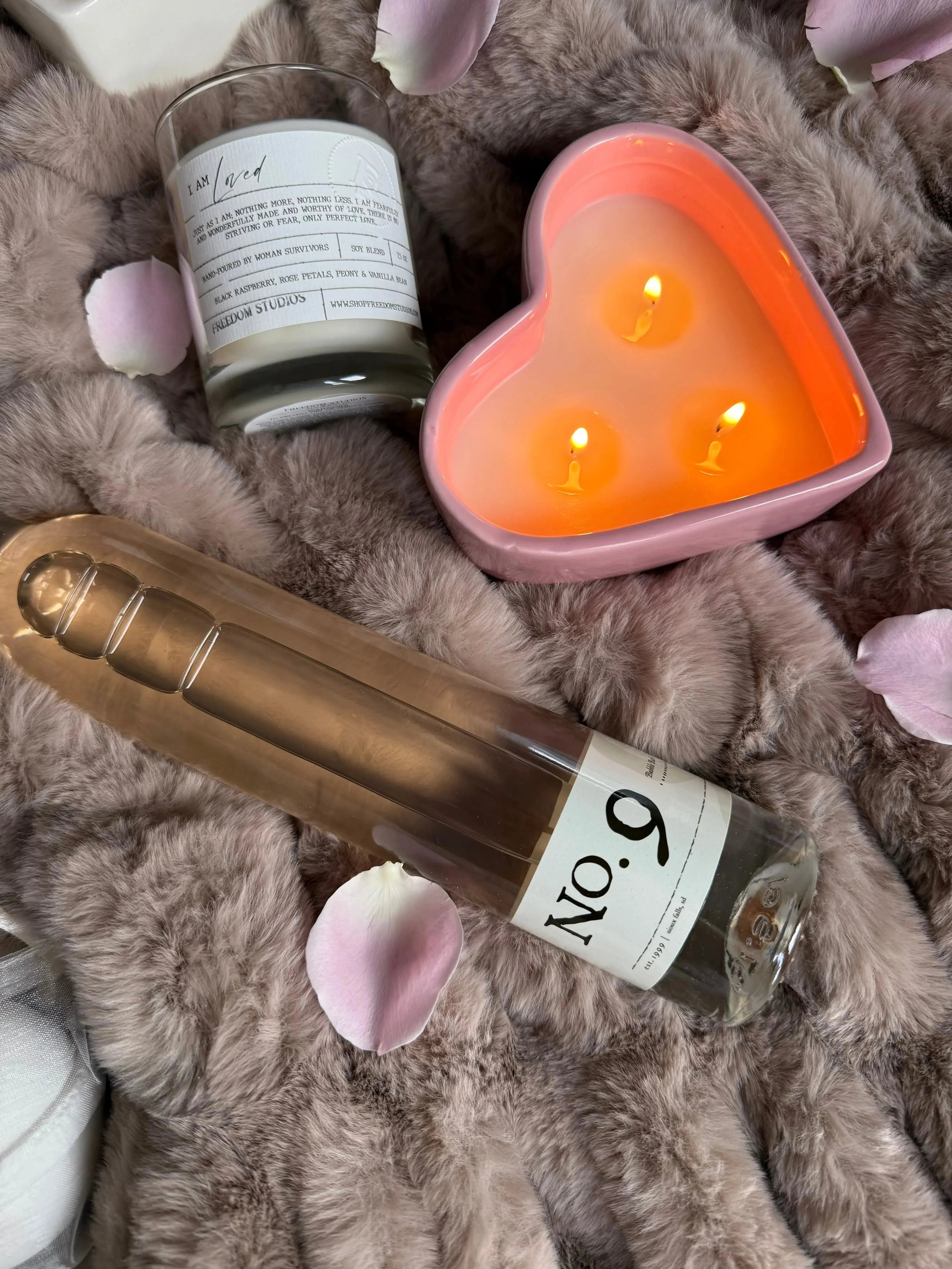 Cozy farmhouse candle set with heart-shaped soy candle, bath oil, and rose petals on fluffy blanket