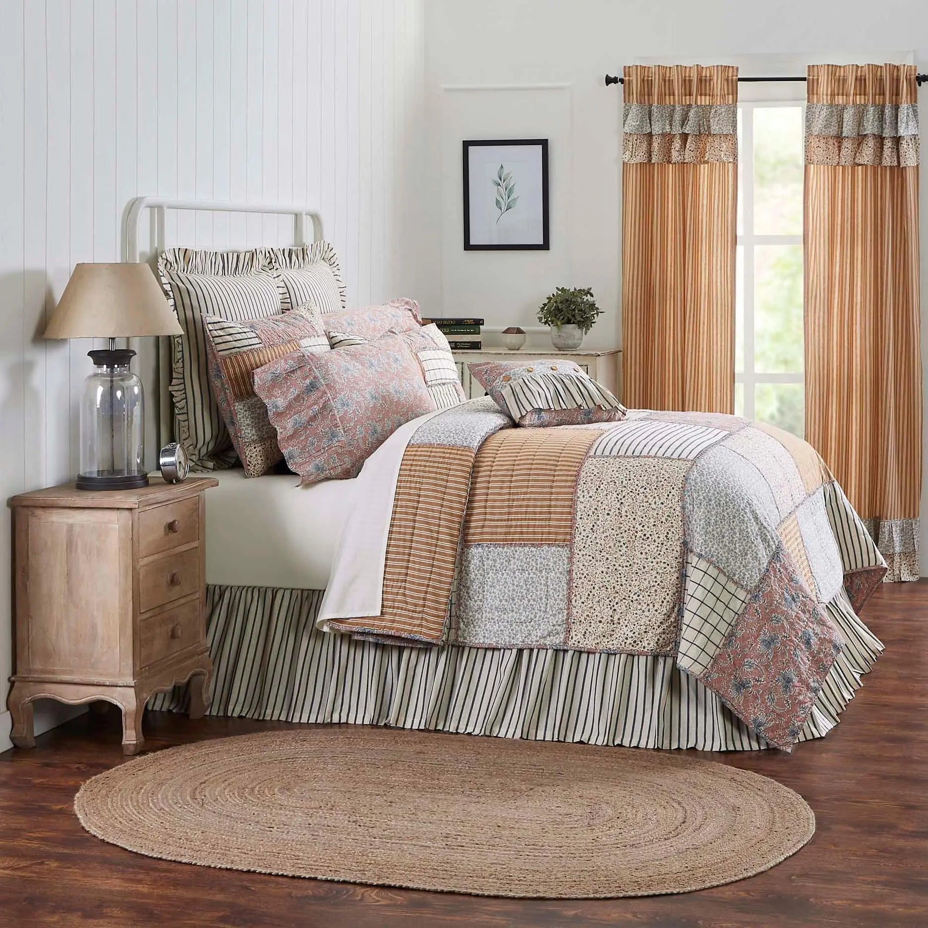 Cozy farmhouse bedroom with patchwork quilt, striped bedding, ruffled curtains, and rustic nightstand