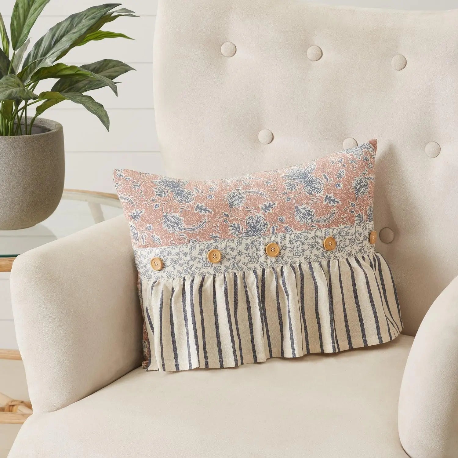 Floral and striped ruffle pillow on cozy farmhouse chair with potted plant