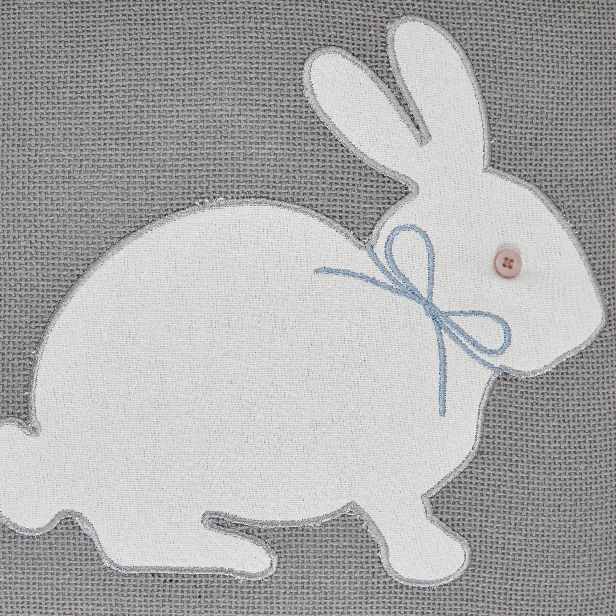 White embroidered bunny with blue bow and button eye on gray fabric, cozy farmhouse decor