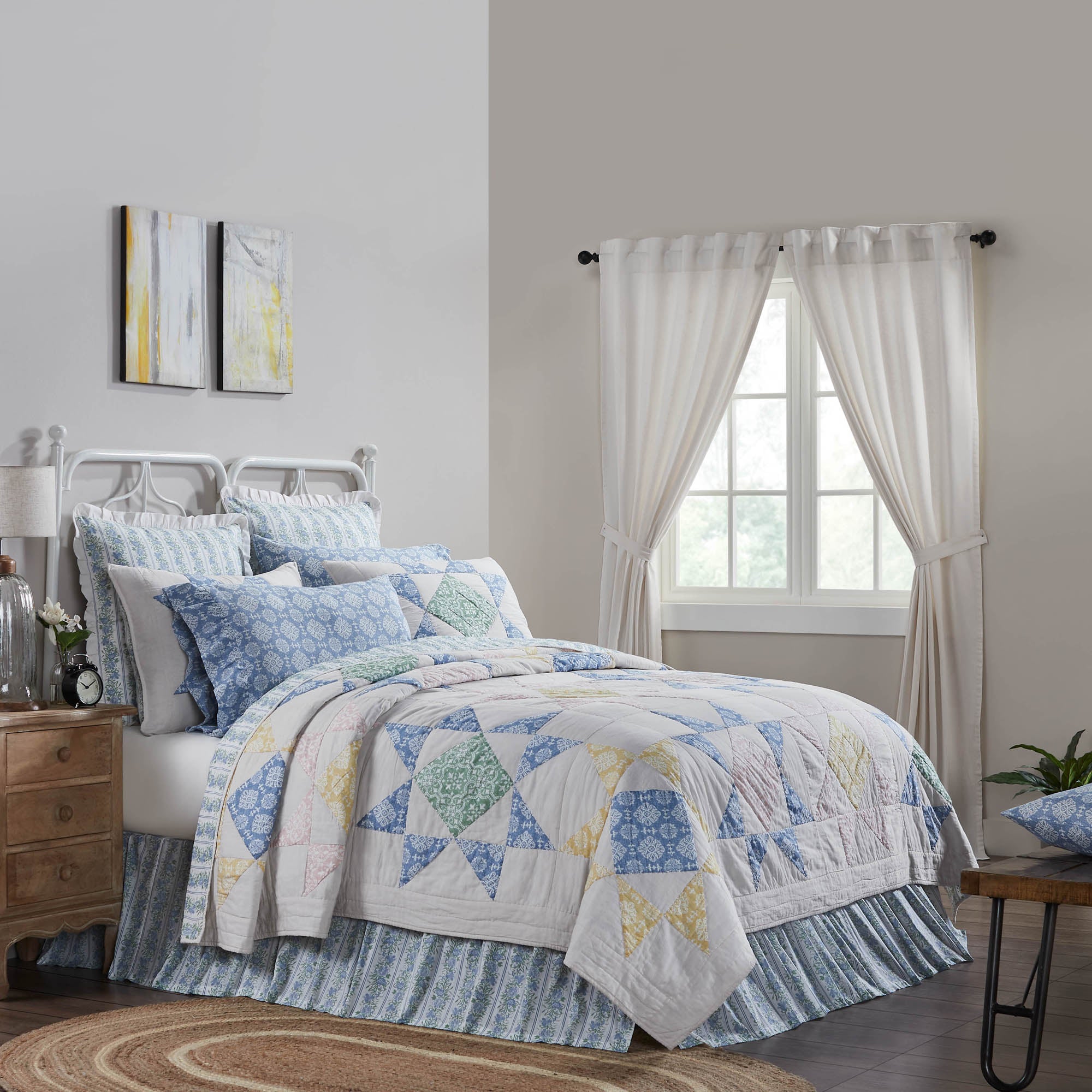 Bedroom with a colorful quilt on a bed, wooden nightstands, and white curtains.