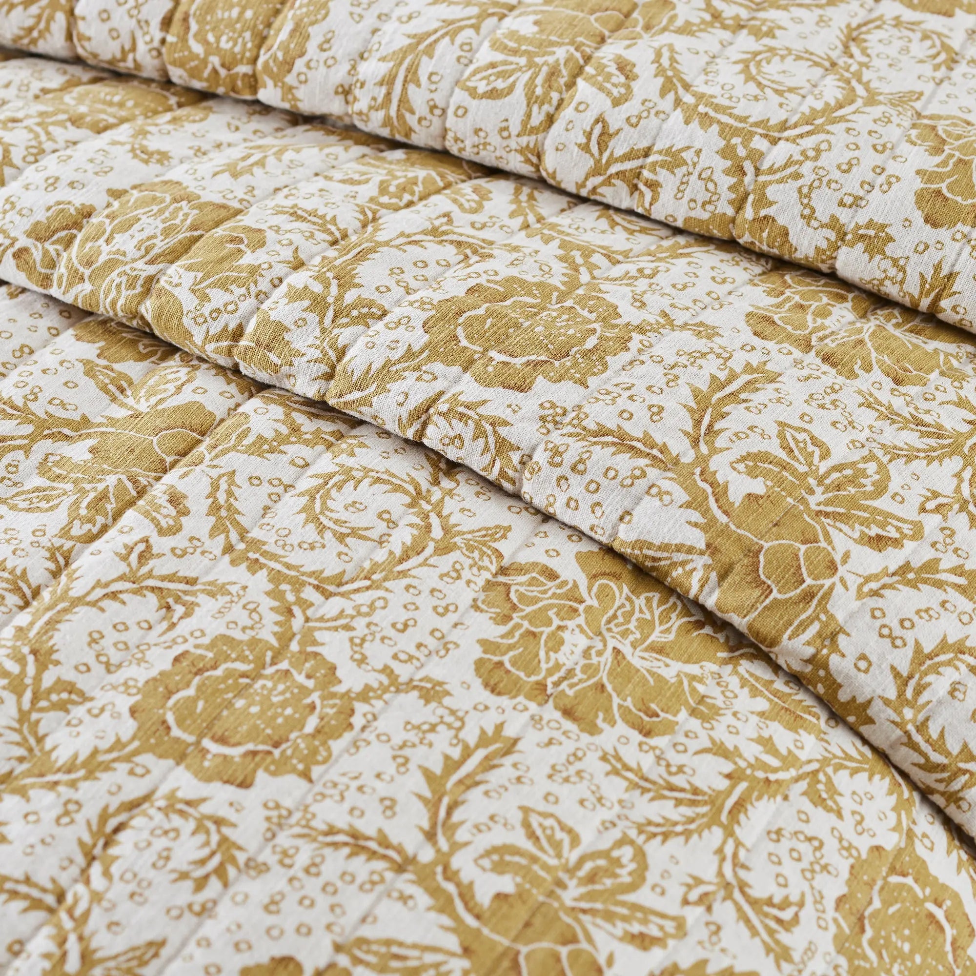 Roll of fabric with gold floral pattern on a white background