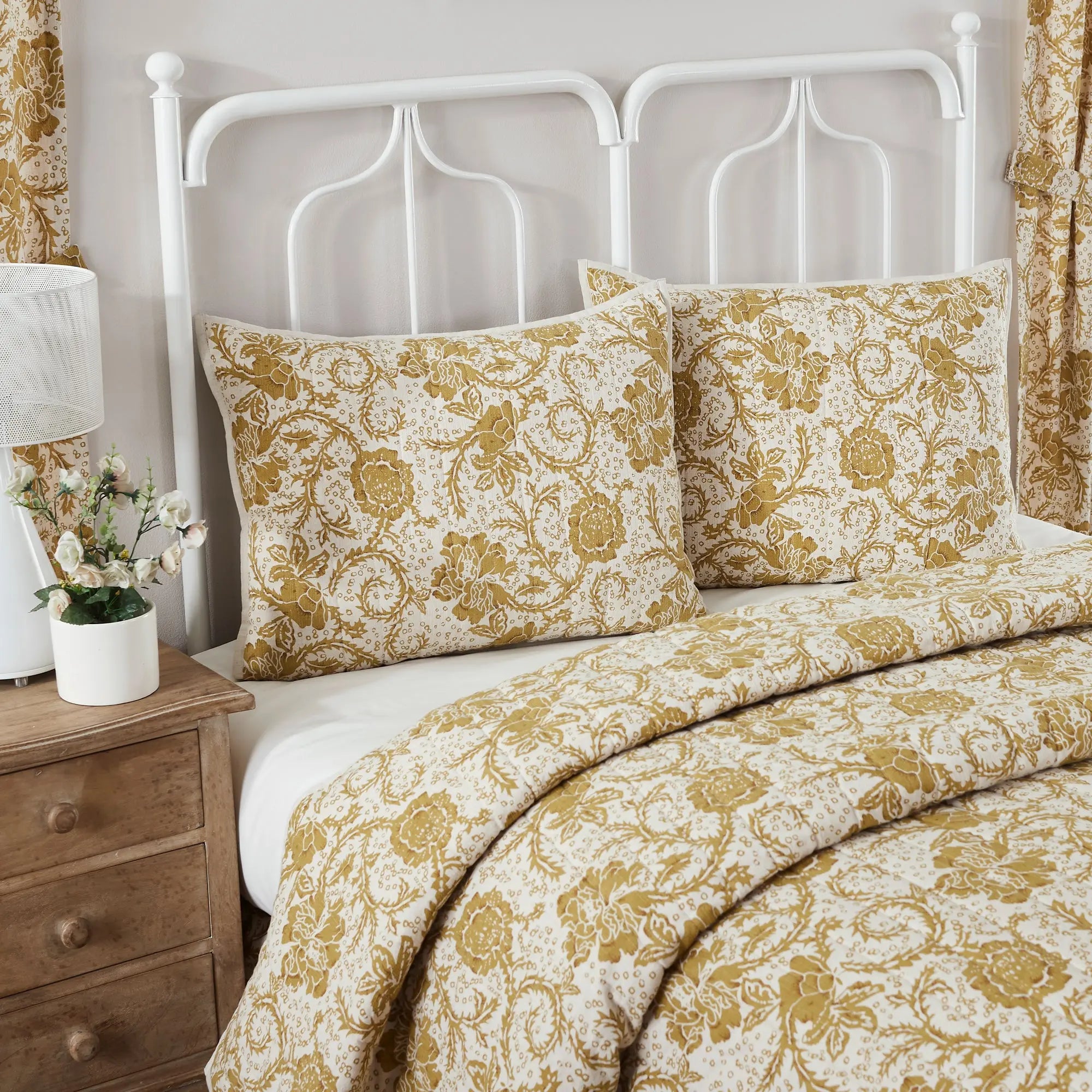Bed with floral bedding and white headboard in a bedroom setting