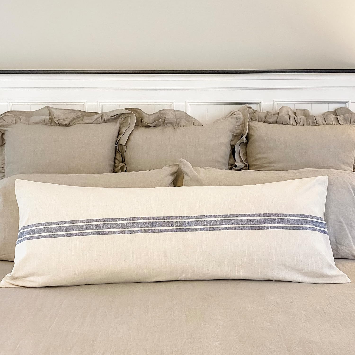 Neatly arranged pillows on a bed with a neutral color scheme.