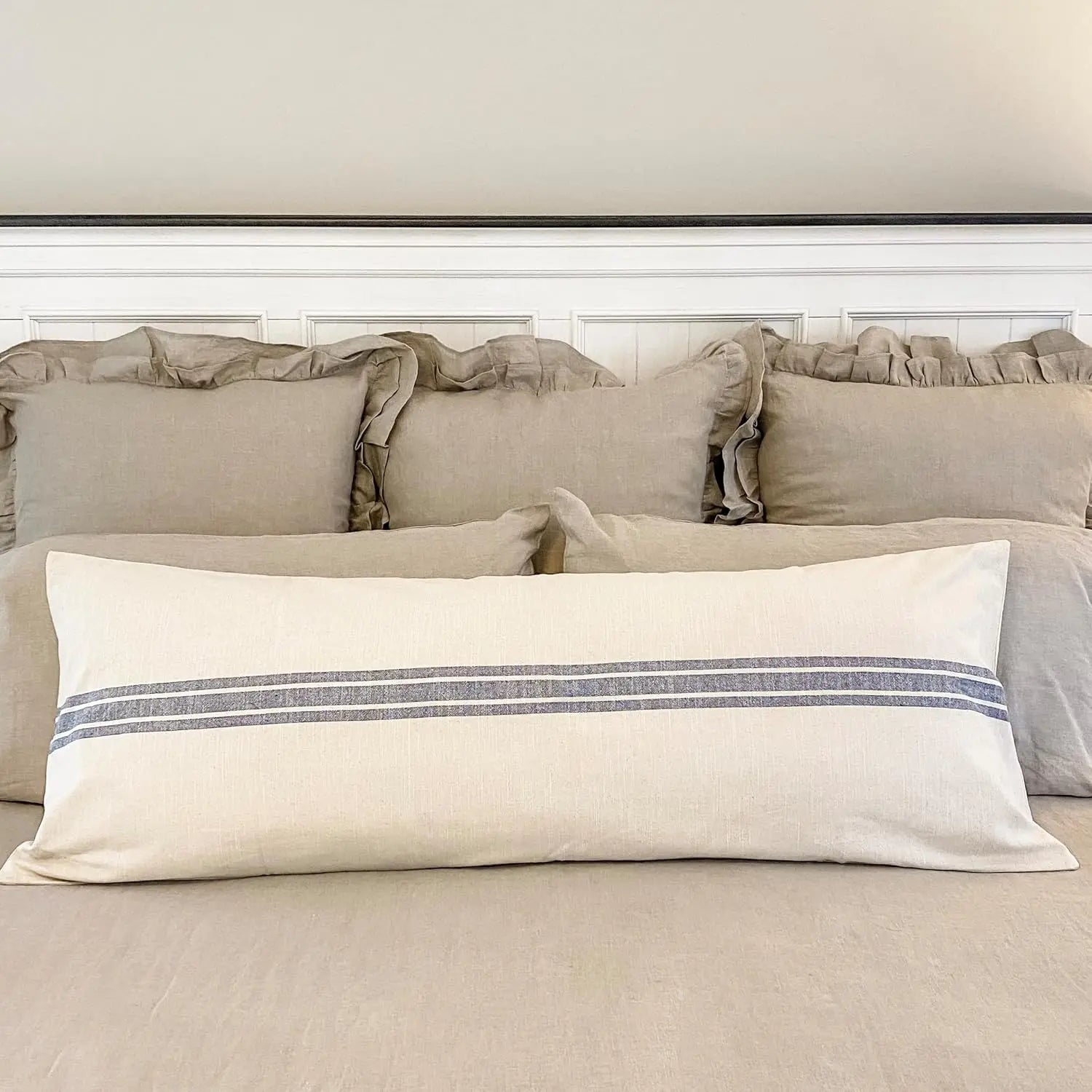 Neatly arranged pillows on a bed with a neutral color scheme.