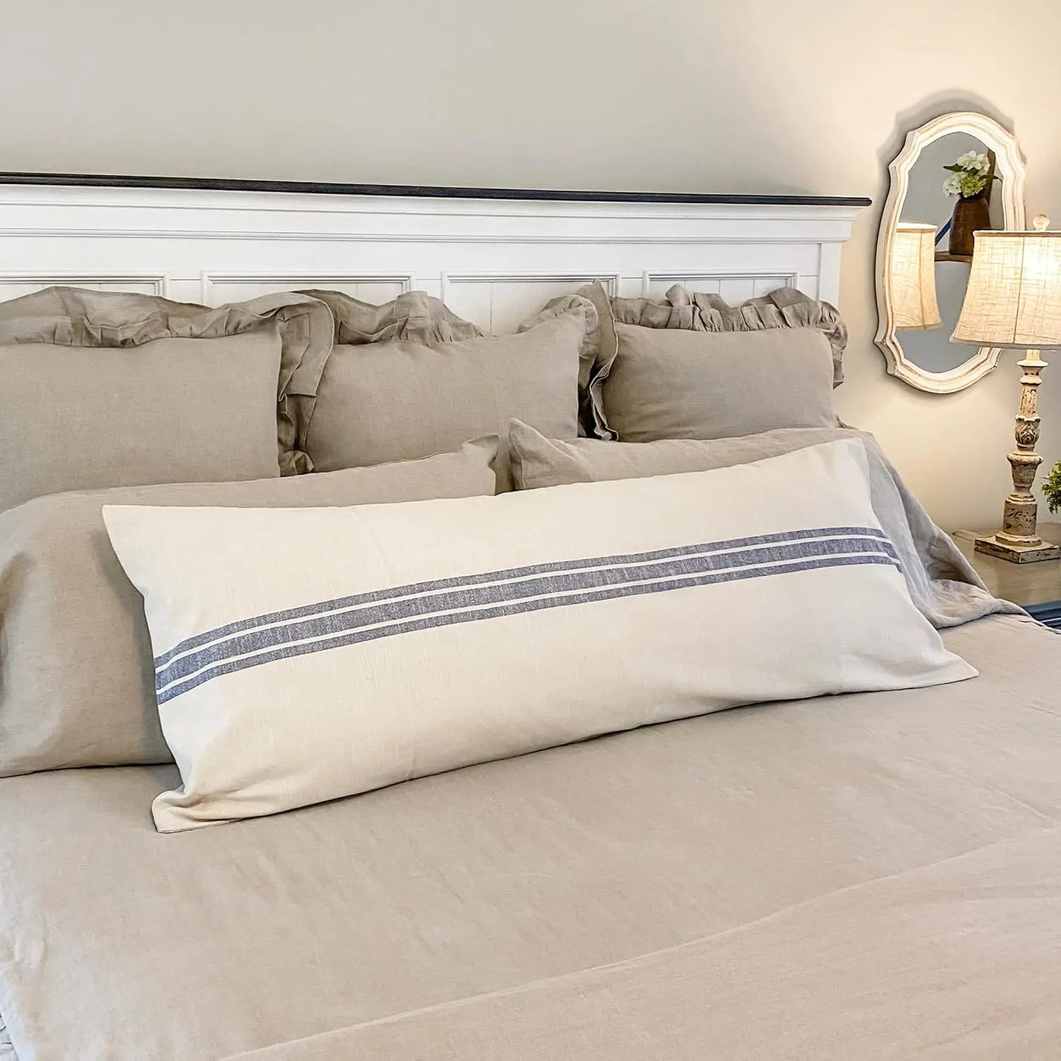 Neatly made bed with beige bedding and decorative pillow in a bedroom setting.