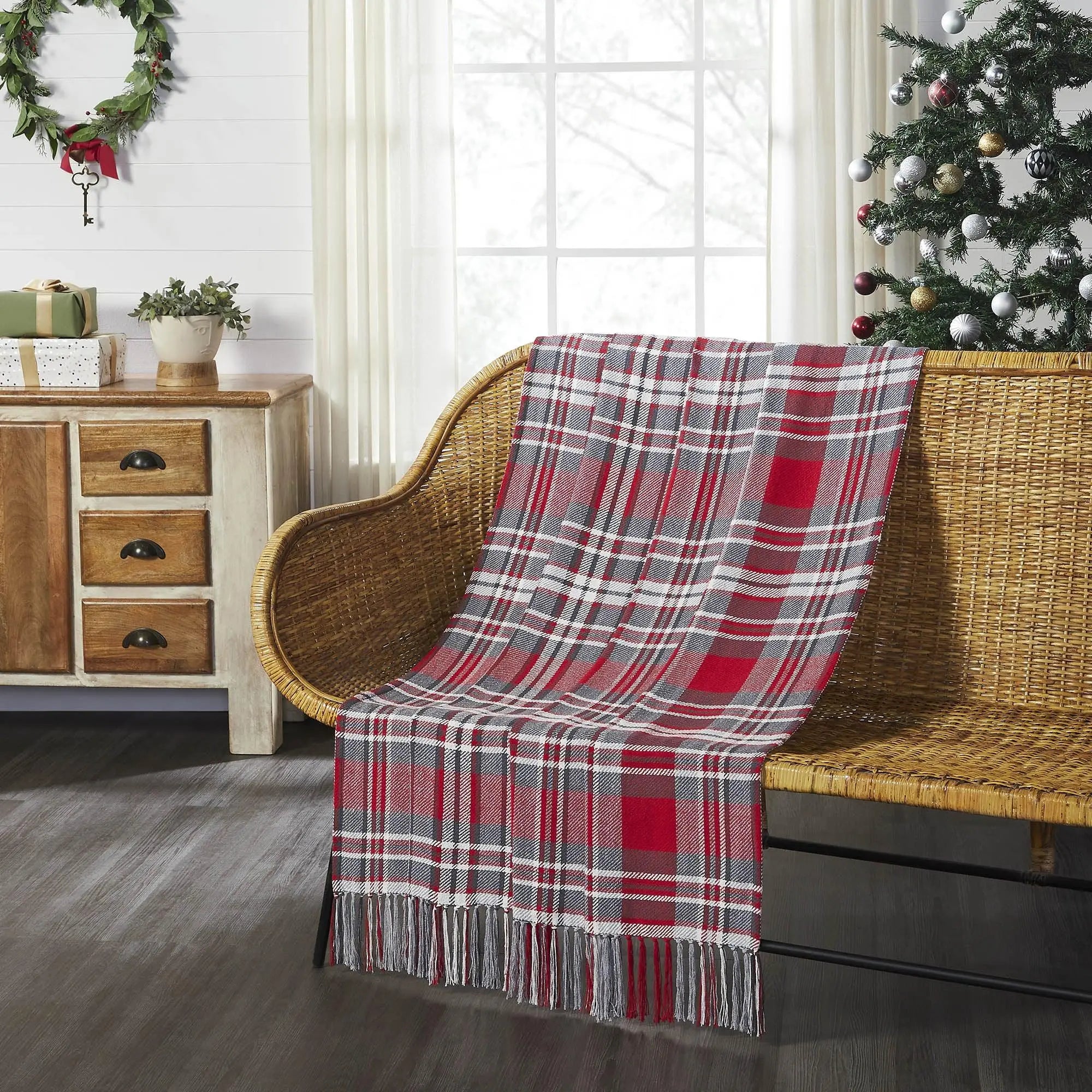 Red and gray plaid throw blanket with fringe on wicker chair, cozy farmhouse holiday decor