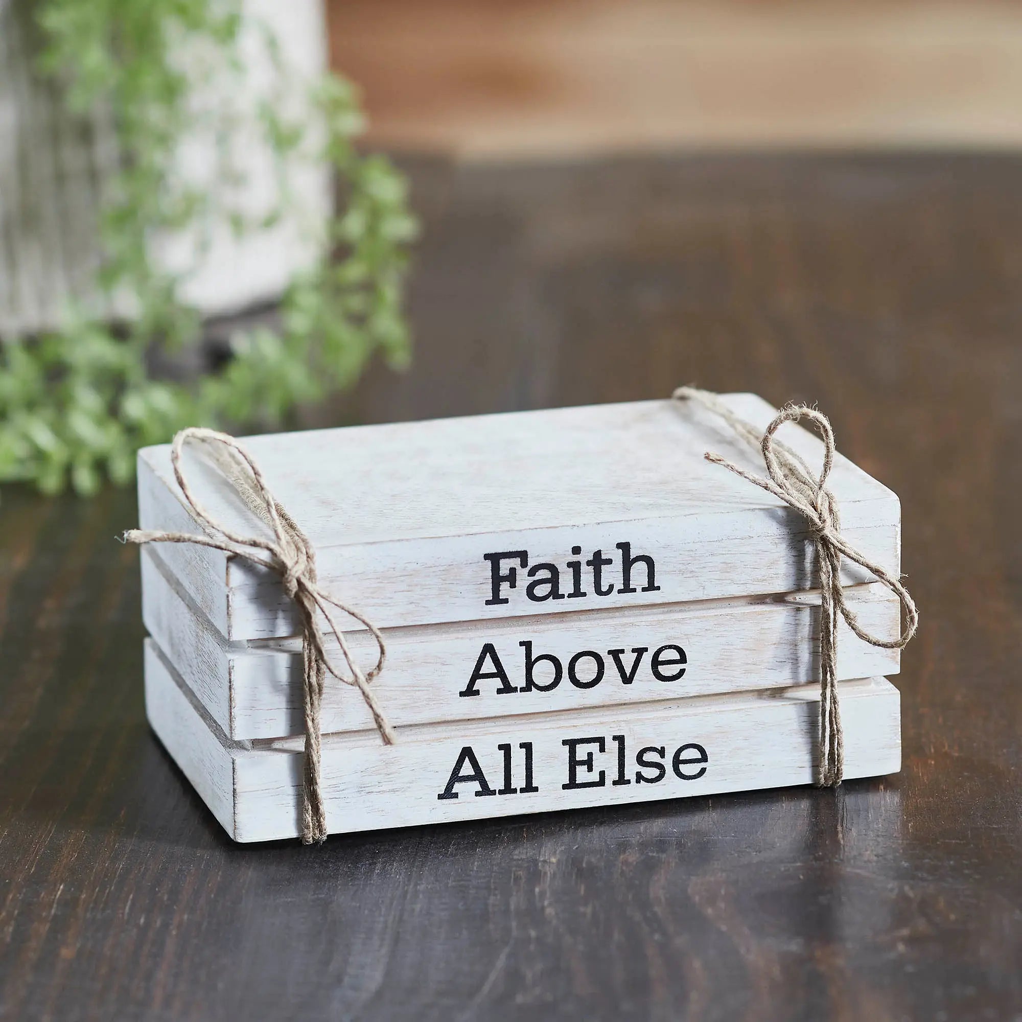 Wooden sign with 'Faith Above All Else' text on a wooden surface.