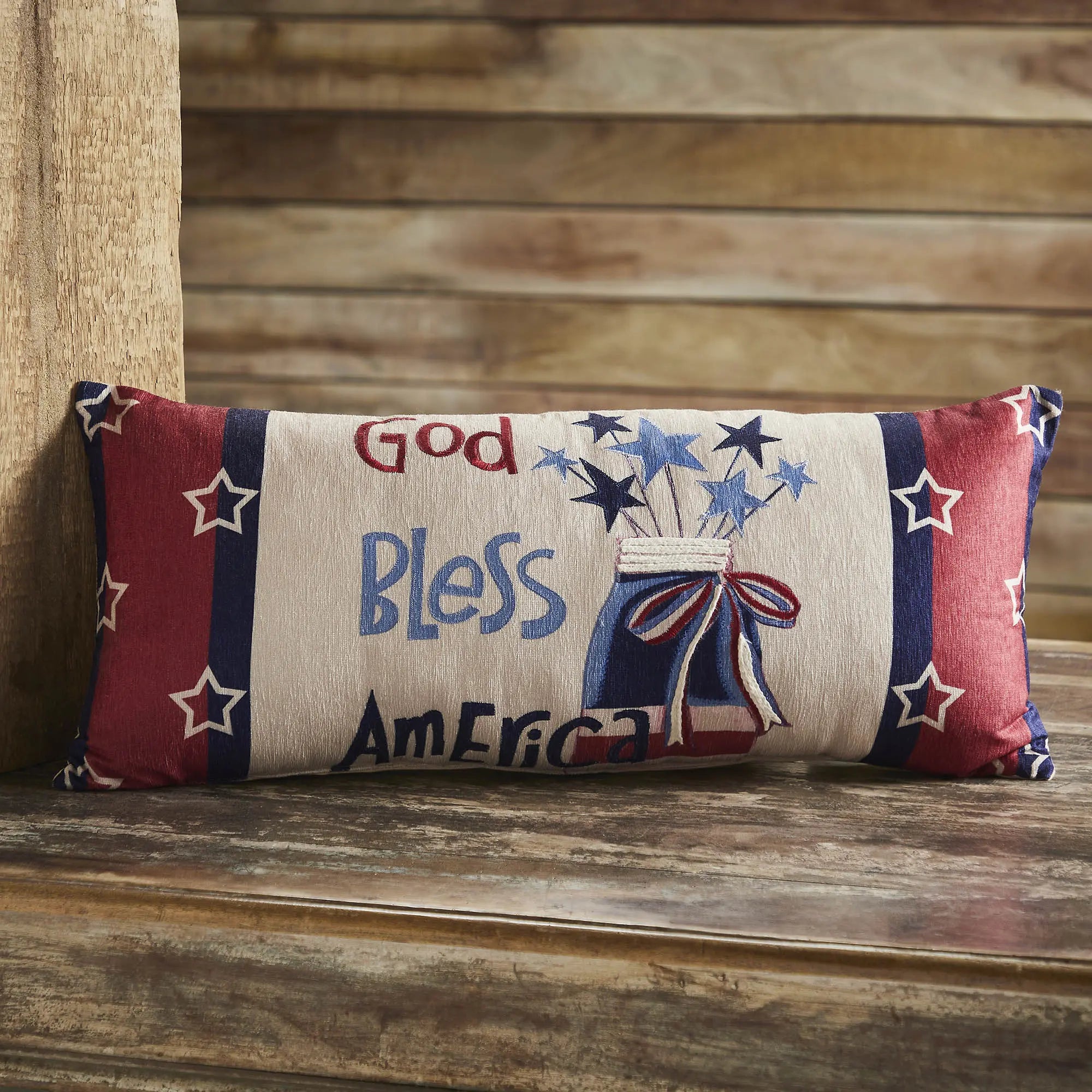 Decorative pillow with 'God Bless America' text on a wooden surface