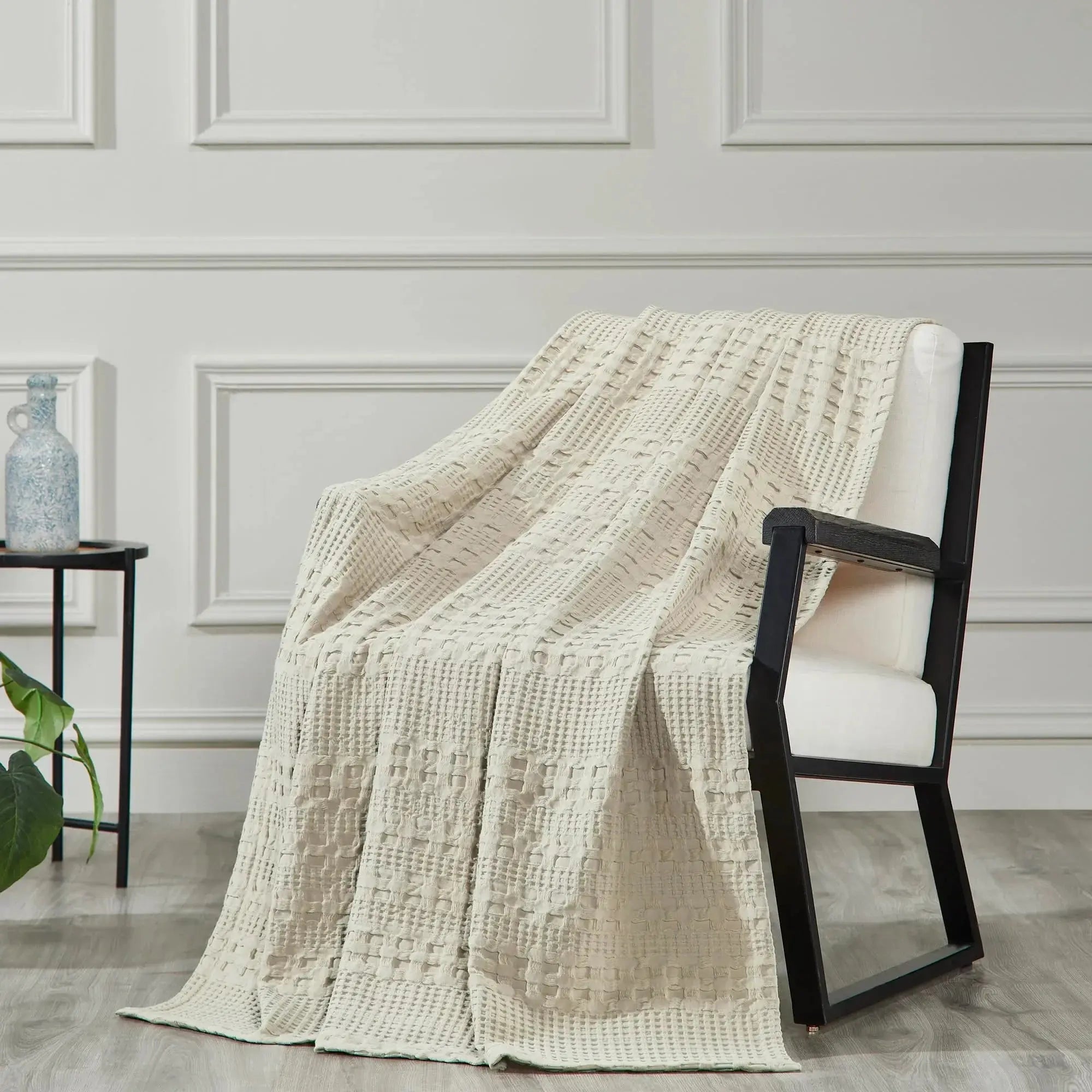 Cream waffle knit throw blanket draped on modern armchair, cozy farmhouse living room decor
