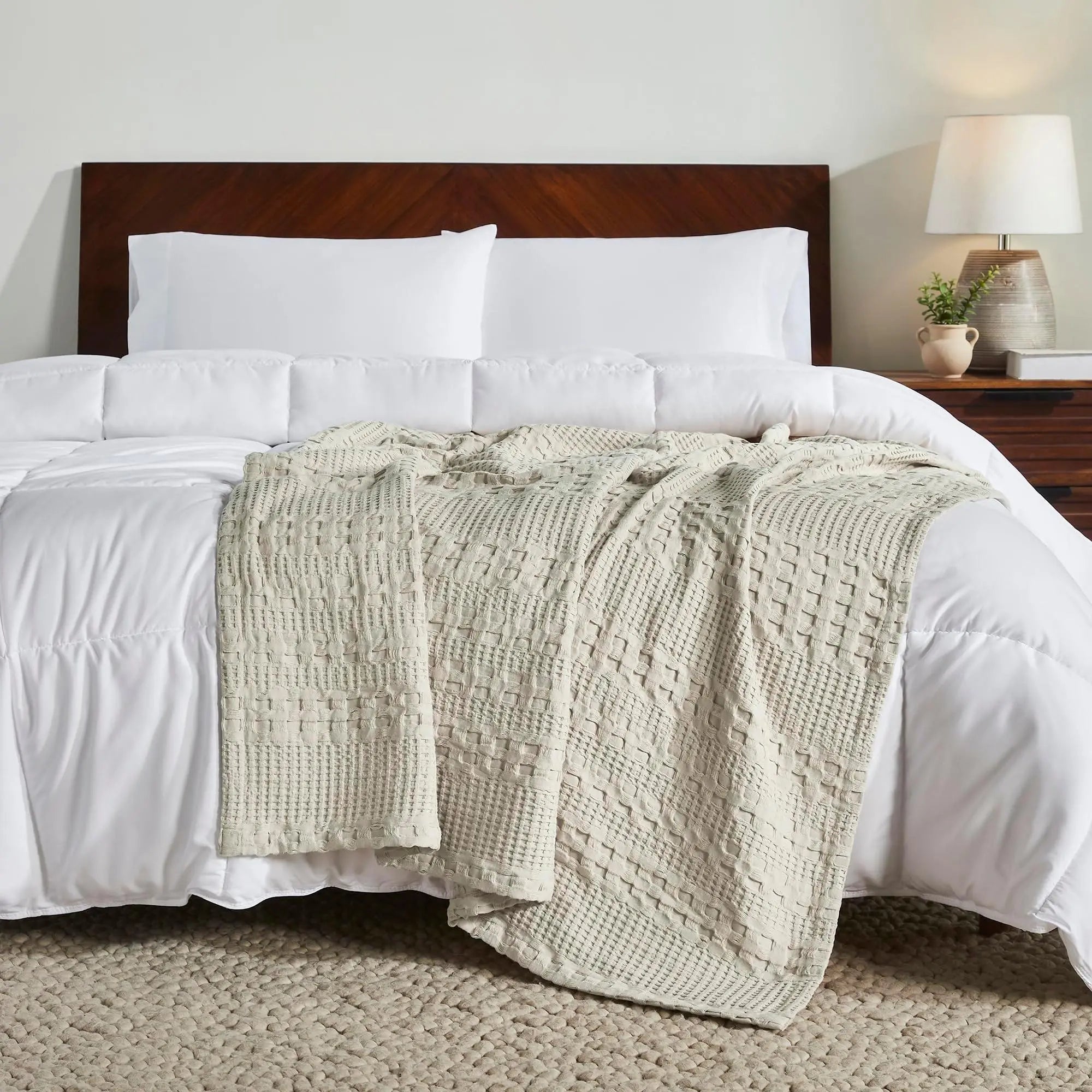 Cozy beige textured throw blanket on white bed, farmhouse style bedroom decor with wooden headboard