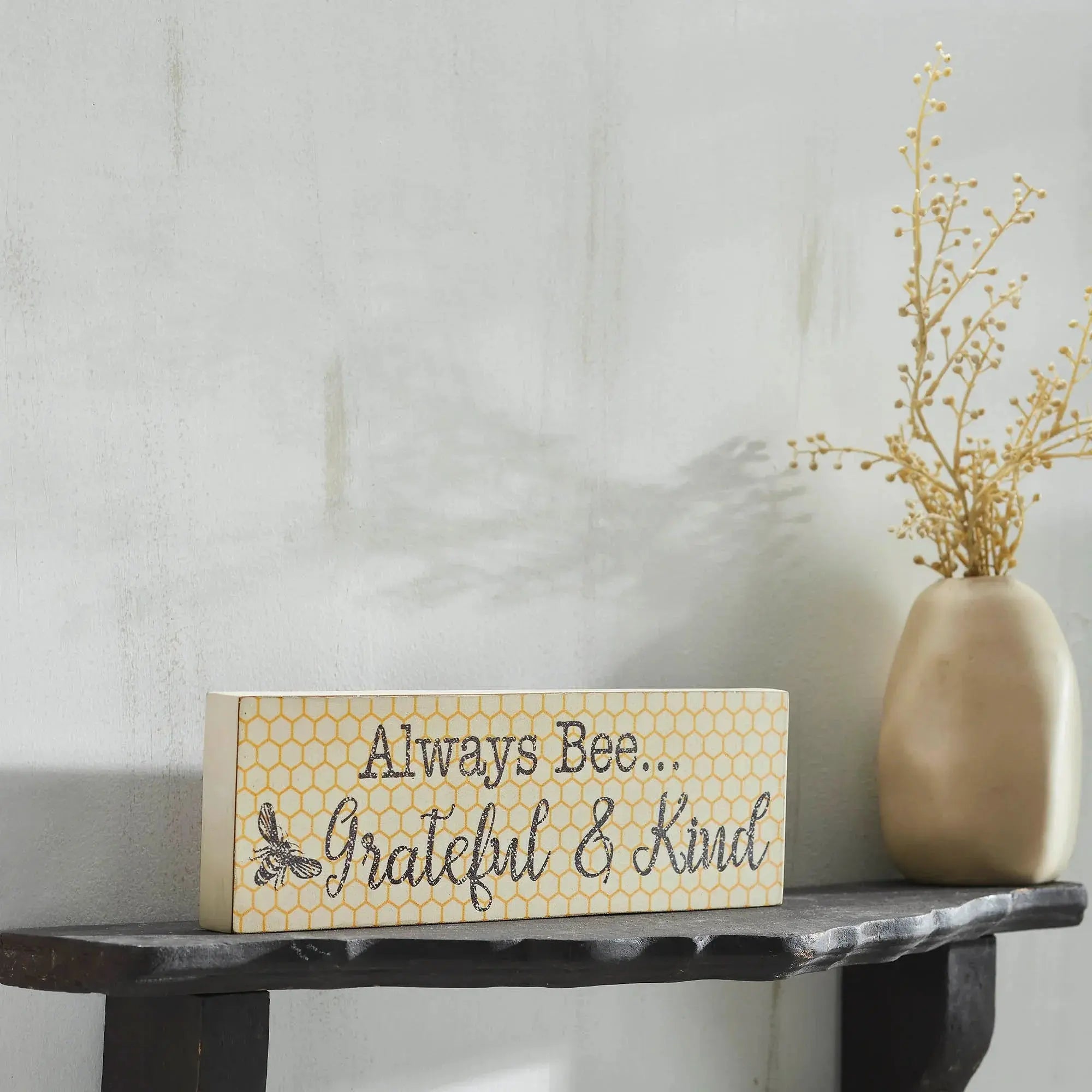 Wooden farmhouse sign with 'Always Bee Grateful & Kind' text, honeycomb pattern, and bee graphic on shelf