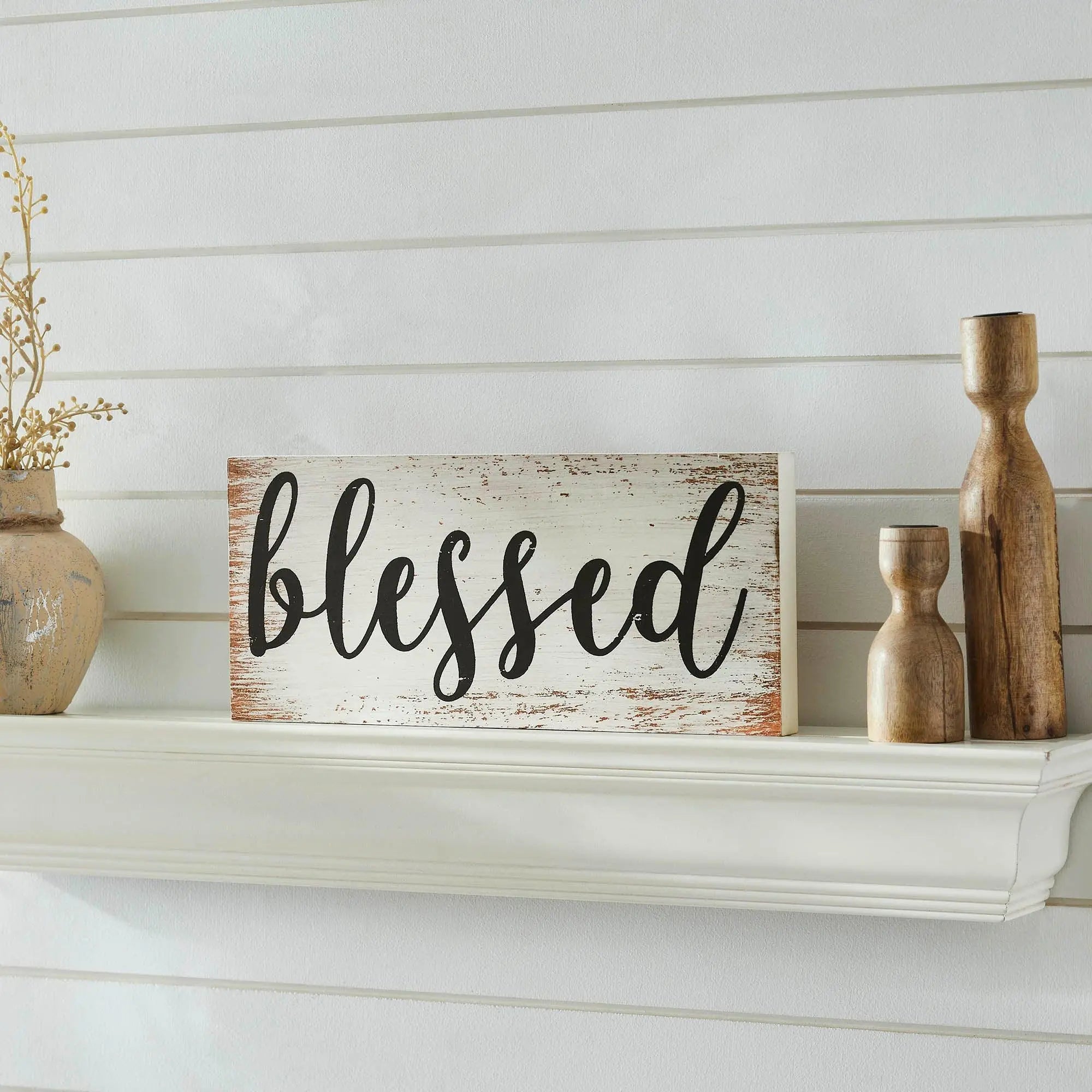 Rustic 'blessed' wood sign on white shelf with farmhouse decor, wooden candle holders, and dried branches