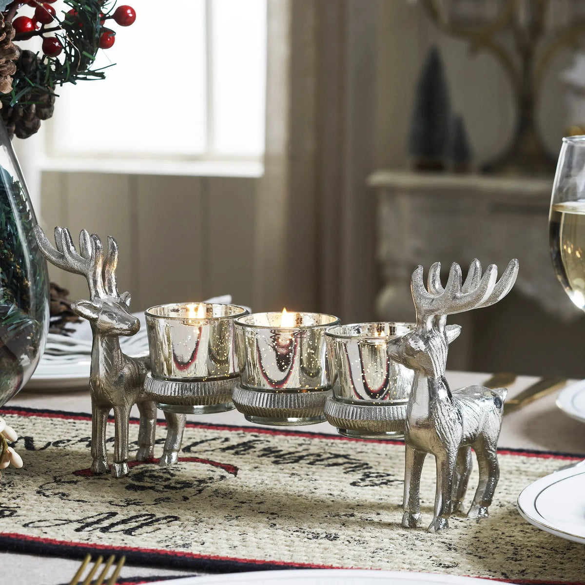 Decorative silver reindeer candle holders on a table with a festive setting.